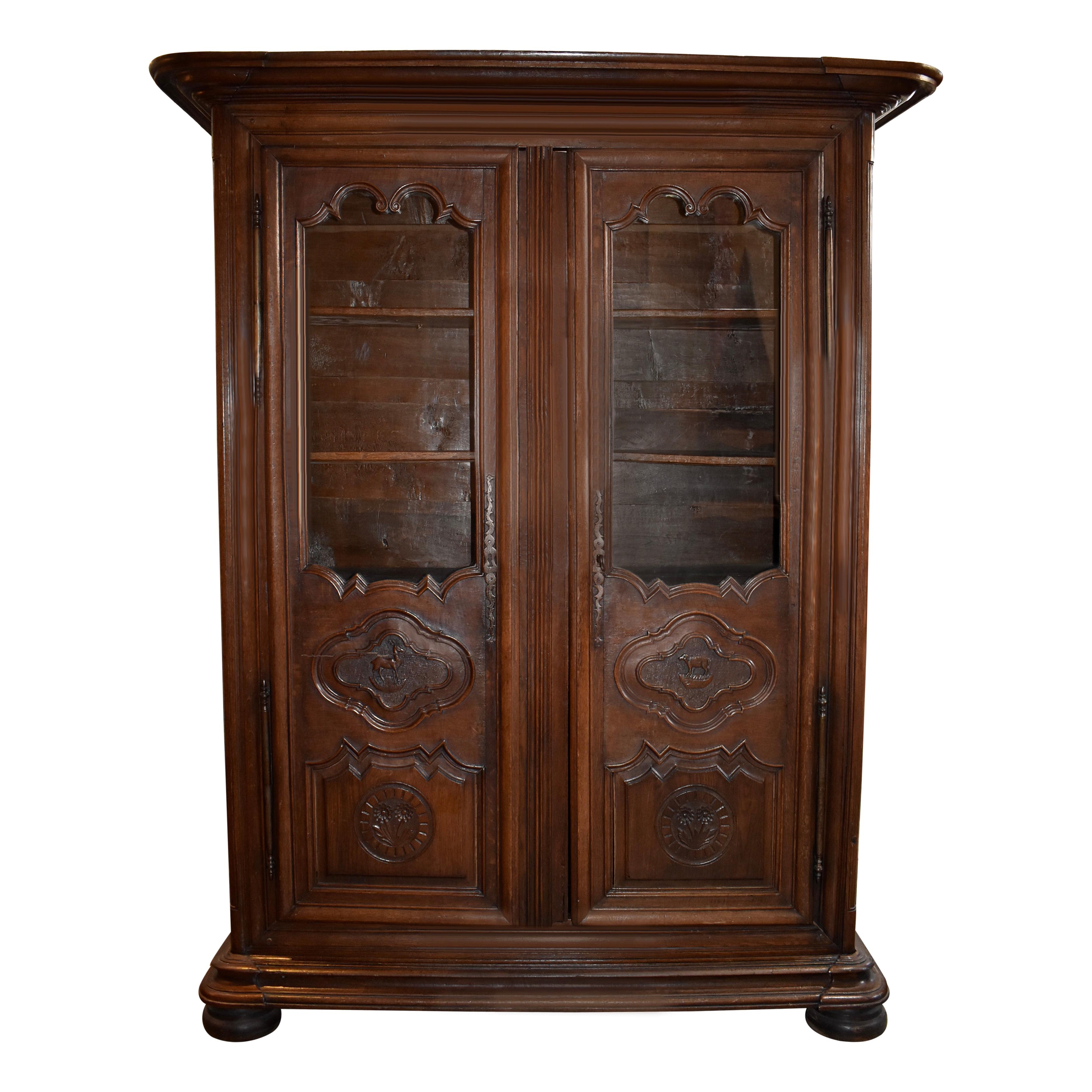 This beautiful oak bookcase showcases two glass front doors with carved lower door panels, one with a carved roe deer to symbolize Belgium's native animals the other with a carved lamb to symbolize its domesticated animals. The doors open to three