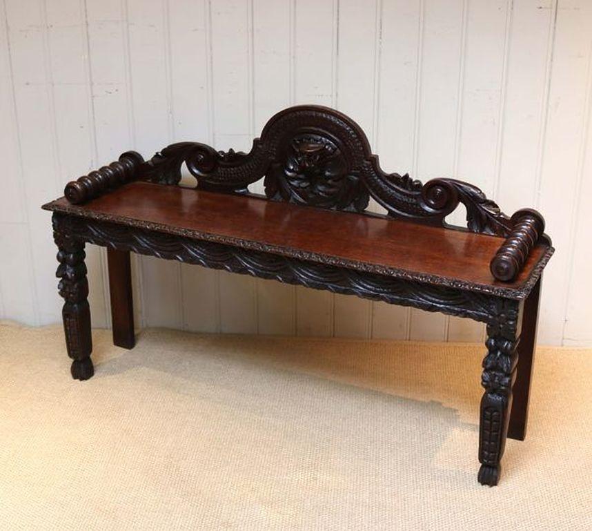 Gothic oak bench having a carved back splat with a solid oak seat and heavily carved front edge and legs with bobbin turned arm rests.