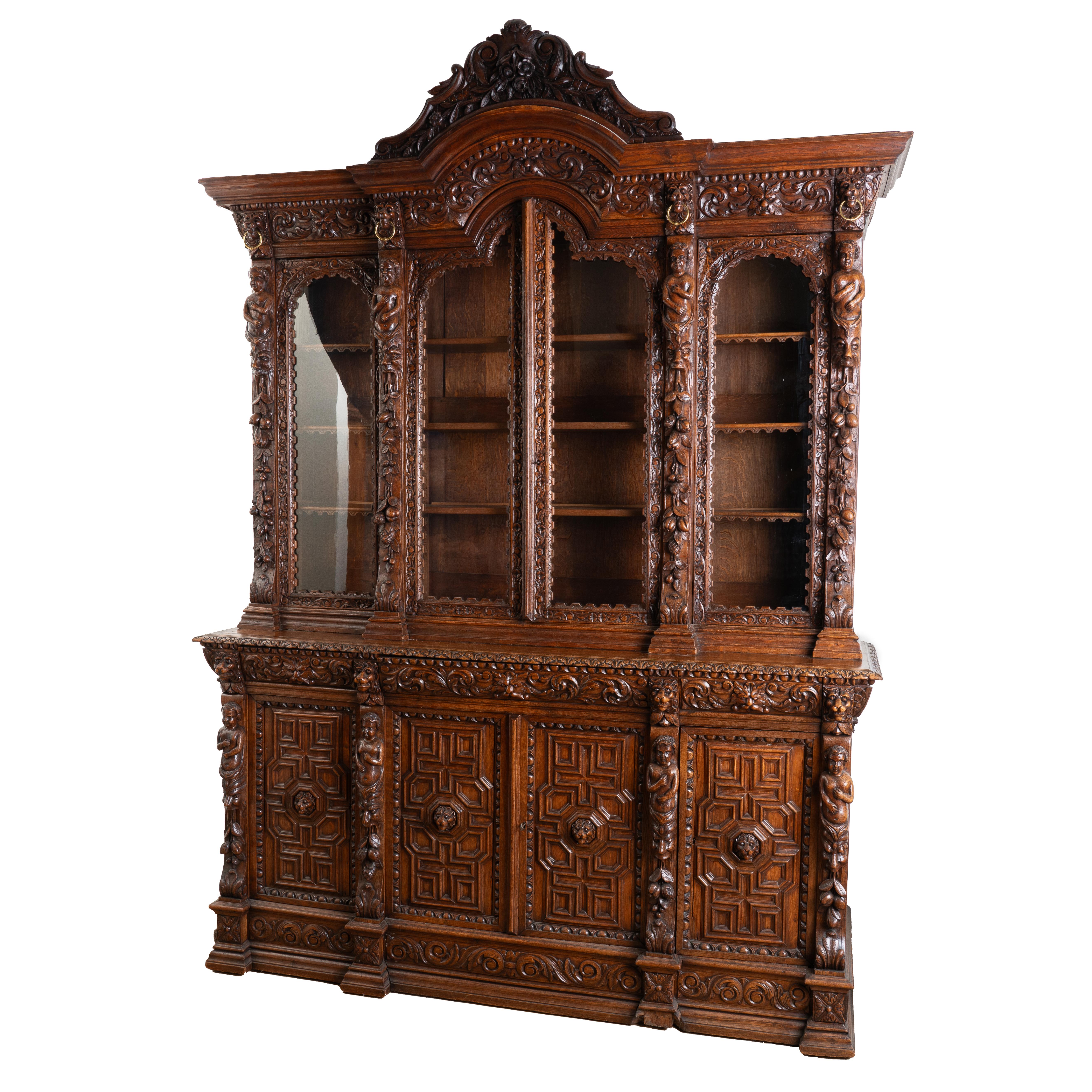 Impressive and statuesque, this extraordinary oak bookcase is embellished with a multitude of carved accents including figures, faces, lion heads, fruit, nuts, leaves and more.
The upper cabinet has 4 glass doors and adjustable shelving which allows