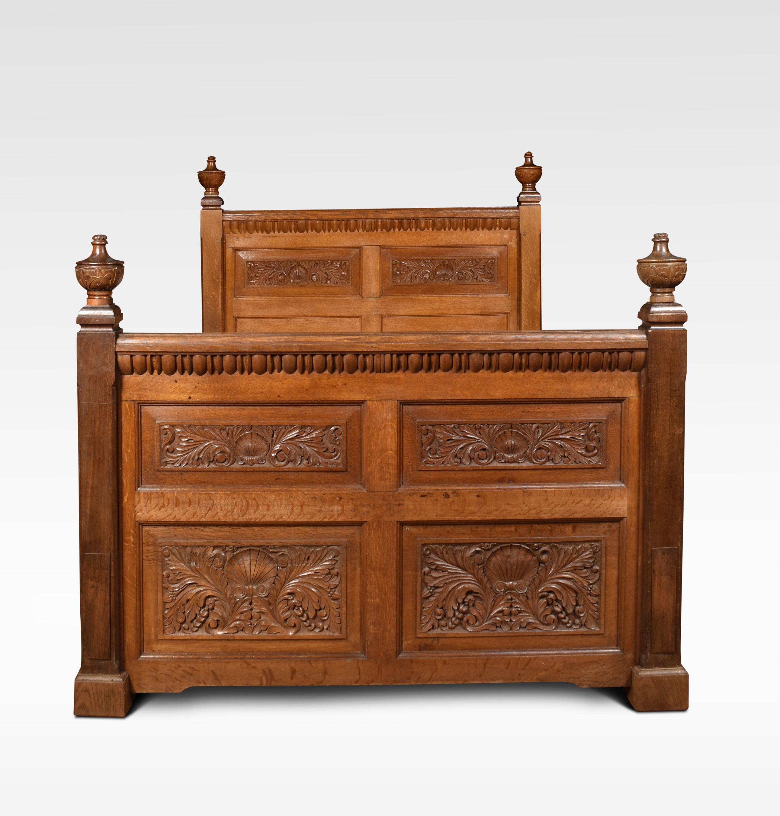 Oak bed the headboard with two carved panels within molded borders, with two plain rectangular panels below, the square uprights surmounted by leaf carved finials. the footboard with similar finials, above four heavily carved panels with central