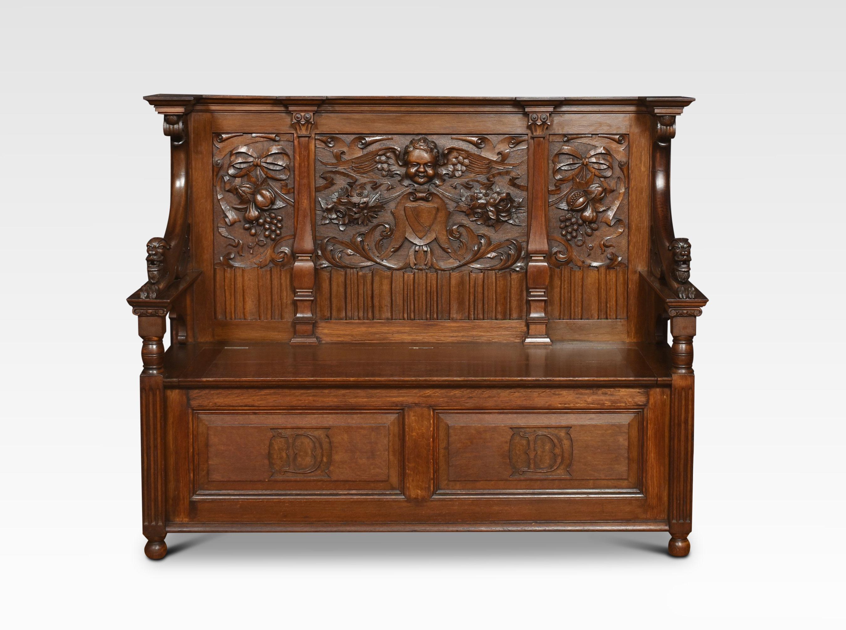 An oak hall settle the carved panelled back with a central cherub head surrounded by scrolling foliated detail. Flanked by lion-headed armrests. To the lift-up seat with a panelled base below all raised up on turned feet.
Dimensions
Height 45