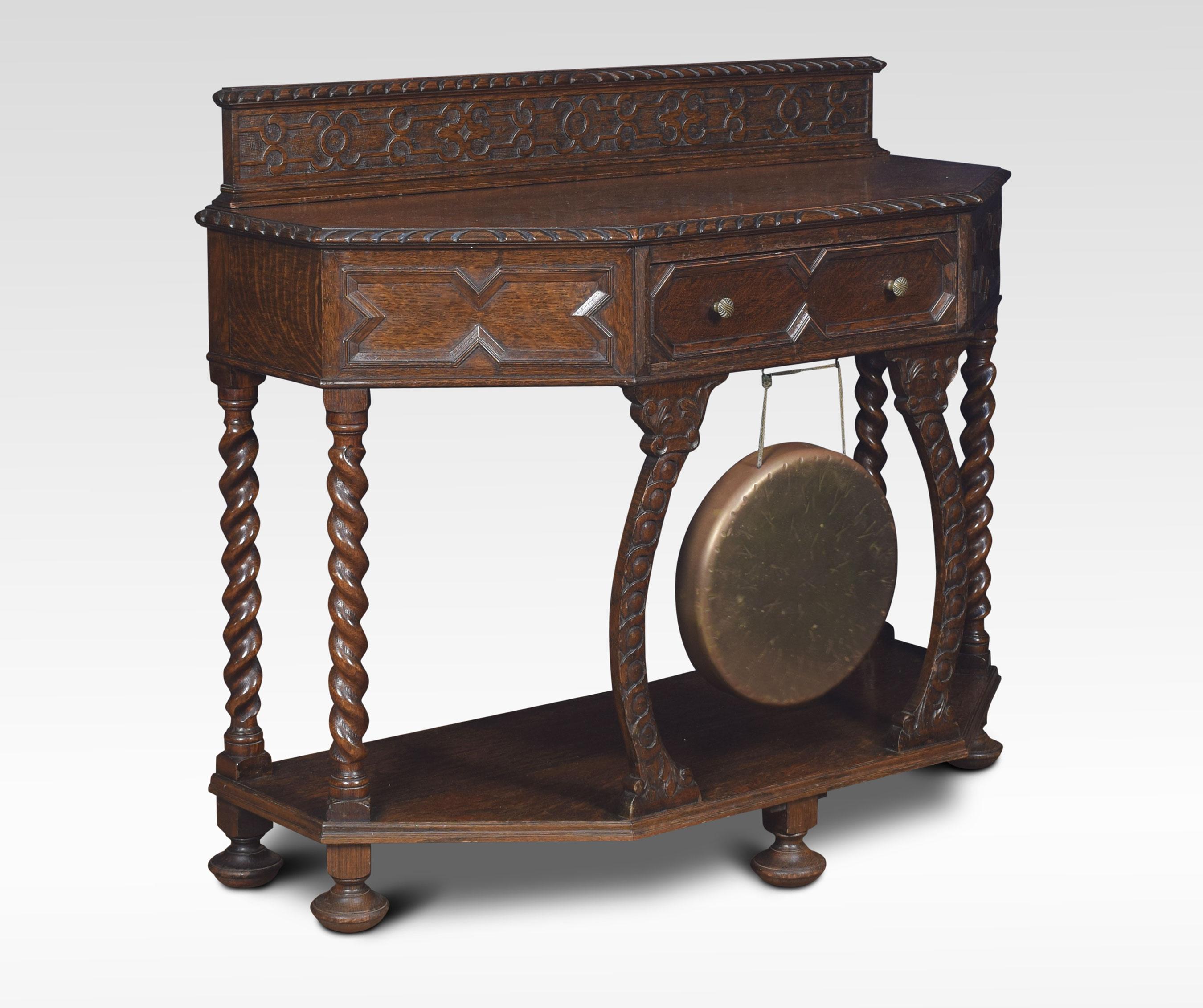 Carved oak hall table, the two of rectangular form with canted corners above a geometric moulded central drawer with brass gong below. Raised up on spiral turned supports united by under tier. All raised up on bun feet.
Dimensions:
Height 36.5
