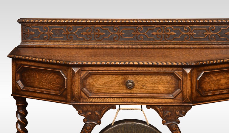 Carved oak hall table of rectangular form with canted corners above a geometric moulded central drawer with brass gong below. Raised up on spiral-turned supports united by under tier. All raised up on bun feet.
Dimensions
Height 35 Inches
Width