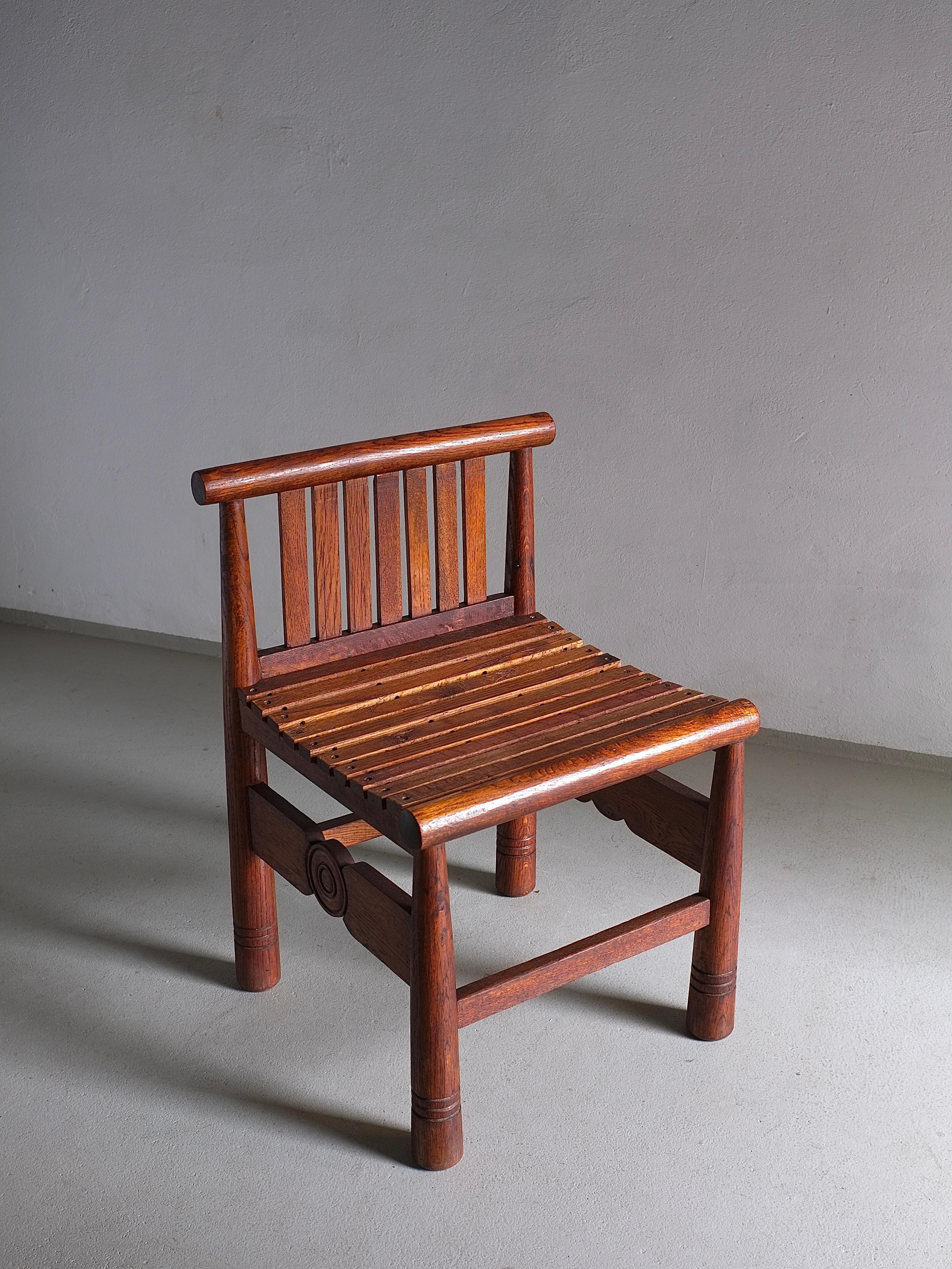 The low back chair has carved details and is made of dark-stained oak. Unique design and craftsmanship. 2 chairs and a bench are available. 