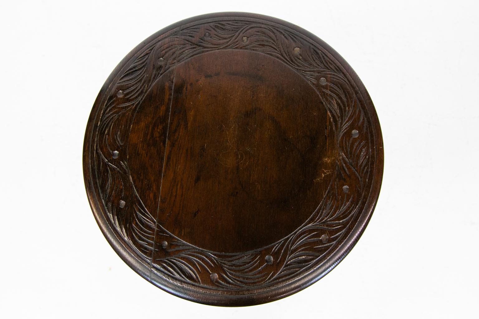 Carved oak occasional table has a repeating carved leaf band around a bull nose edge. The base has a carved and fluted center knop which rests on a carved trefoil platform base.