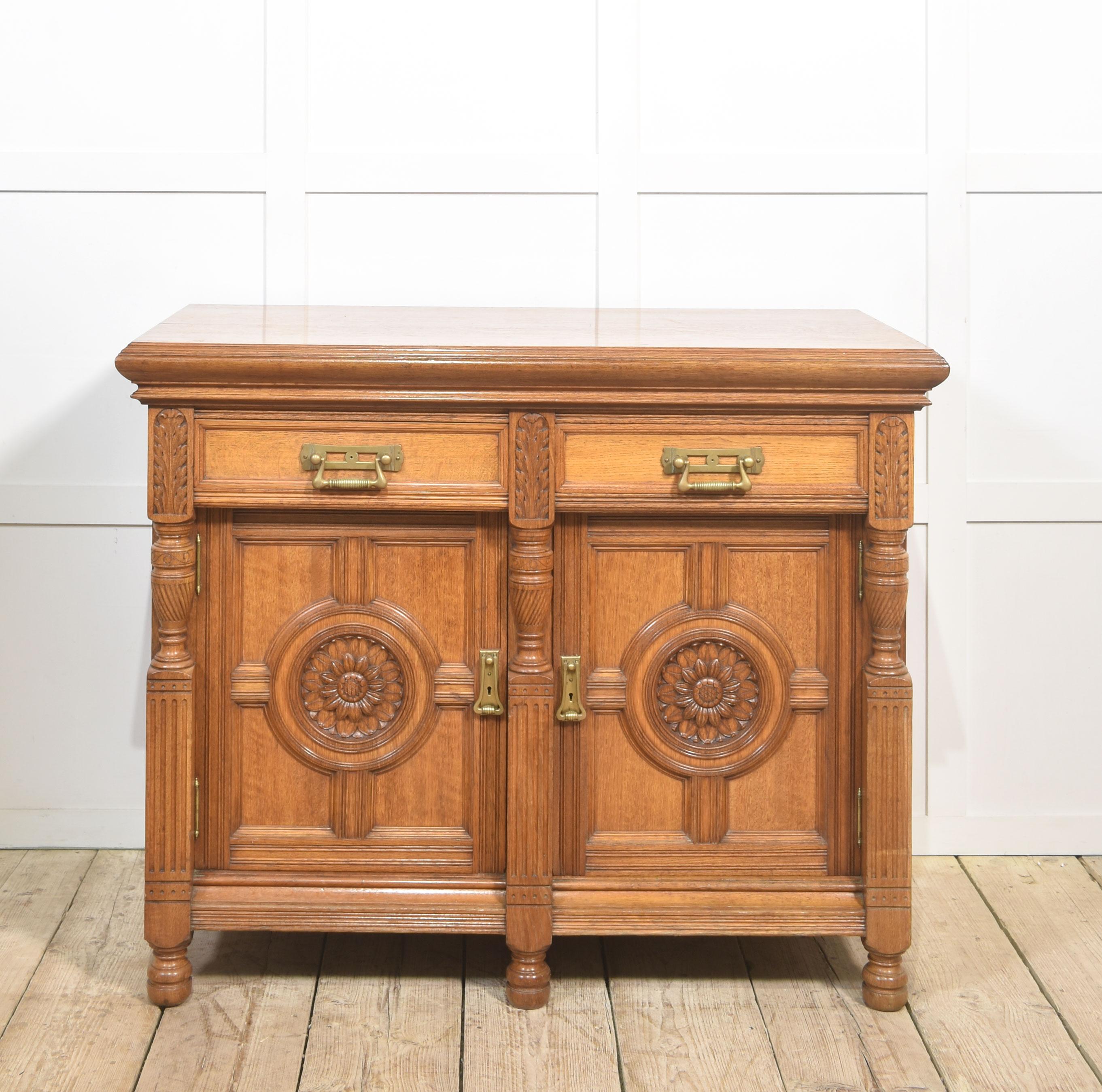 19th-century oak sideboard, the large rectangular top with moulded edge above two freeze drawers fitted with bold brass handles. The base section is fitted with a pair of panelled doors with circular moulded centres with floral carved decoration.