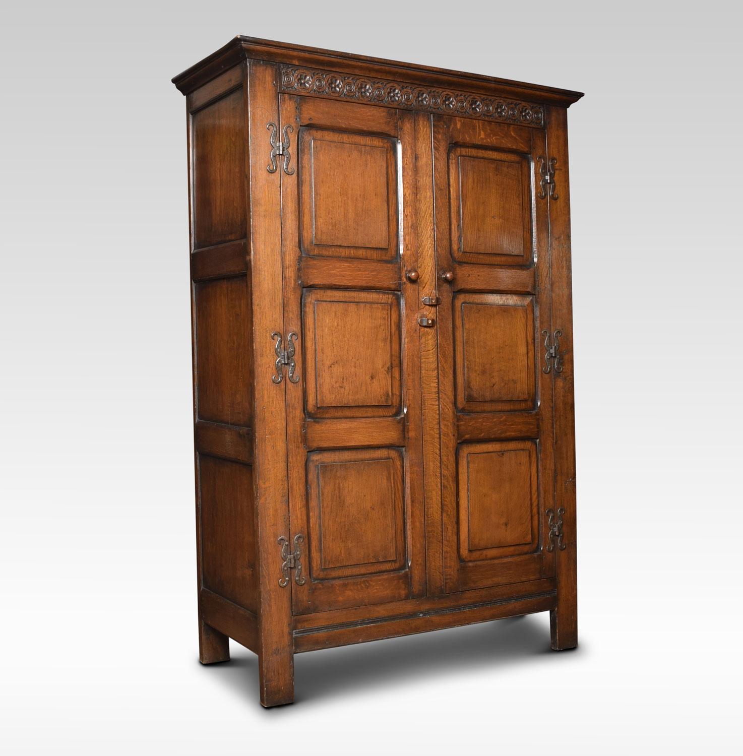 Large solid oak two-door wardrobe, the moulded cornice above linen fold decoration in the Jacobean style. The large panelled doors opening to reveal storage and hanging area, raised up on bracket feet
Dimensions
Height 73 inches
Width 49