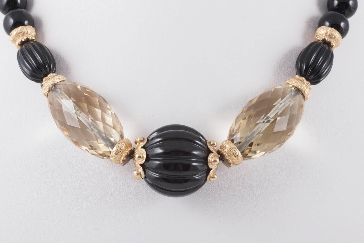 This is a smart handmade necklace from the 1980s, featuring faceted citrines of a lovely pale golden yellow and both smooth onyx beads and ribbed larger beads. The fittings are well cast high quality silver gilt. It sits comfortably at the base of