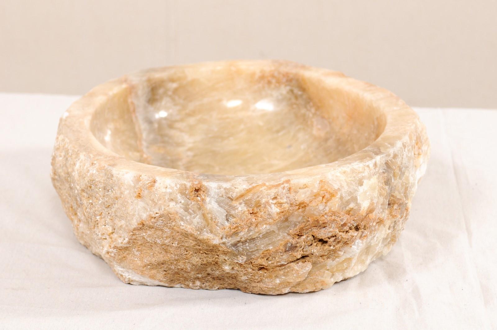 Un seul bassin d'évier en onyx naturel avec bord vif original. Cet évier sculpté, créé à partir d'une roche onyx brute, possède un bassin intérieur sculpté puis poli, ce qui facilite le nettoyage. La pierre naturelle texturée reste sur l'extérieur