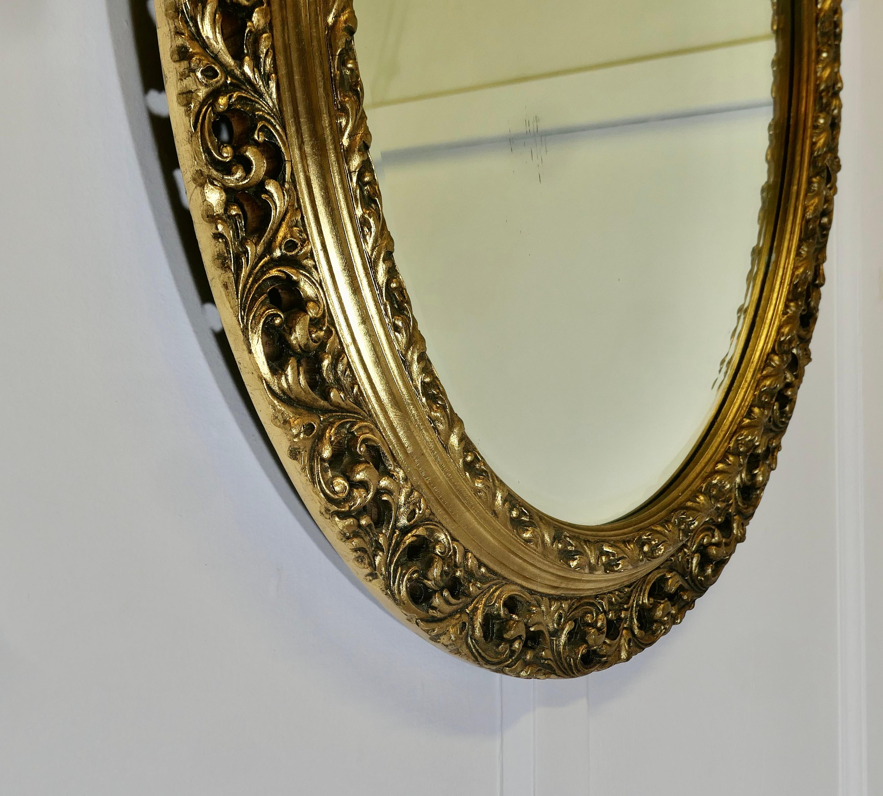 Milieu du XXe siècle Miroir mural ovale sculpté et doré    C'est un miroir très attrayant en vente