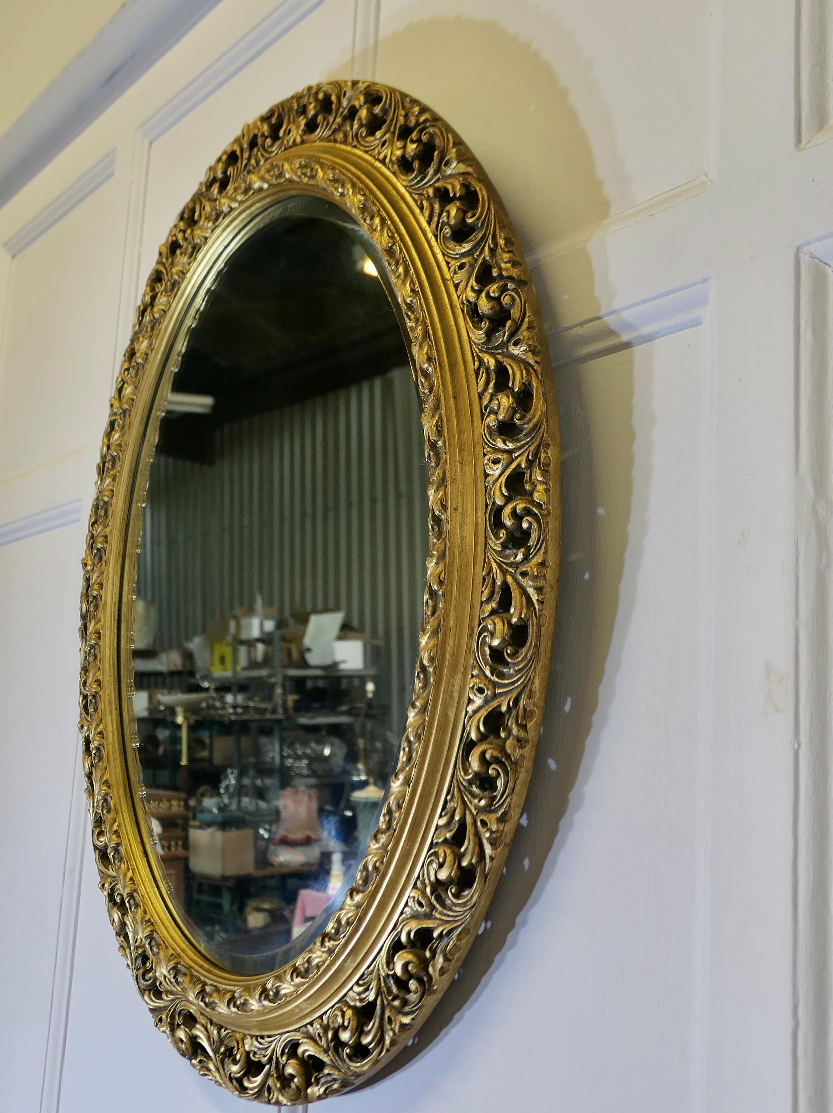 Bois doré Miroir mural ovale sculpté et doré    C'est un miroir très attrayant en vente