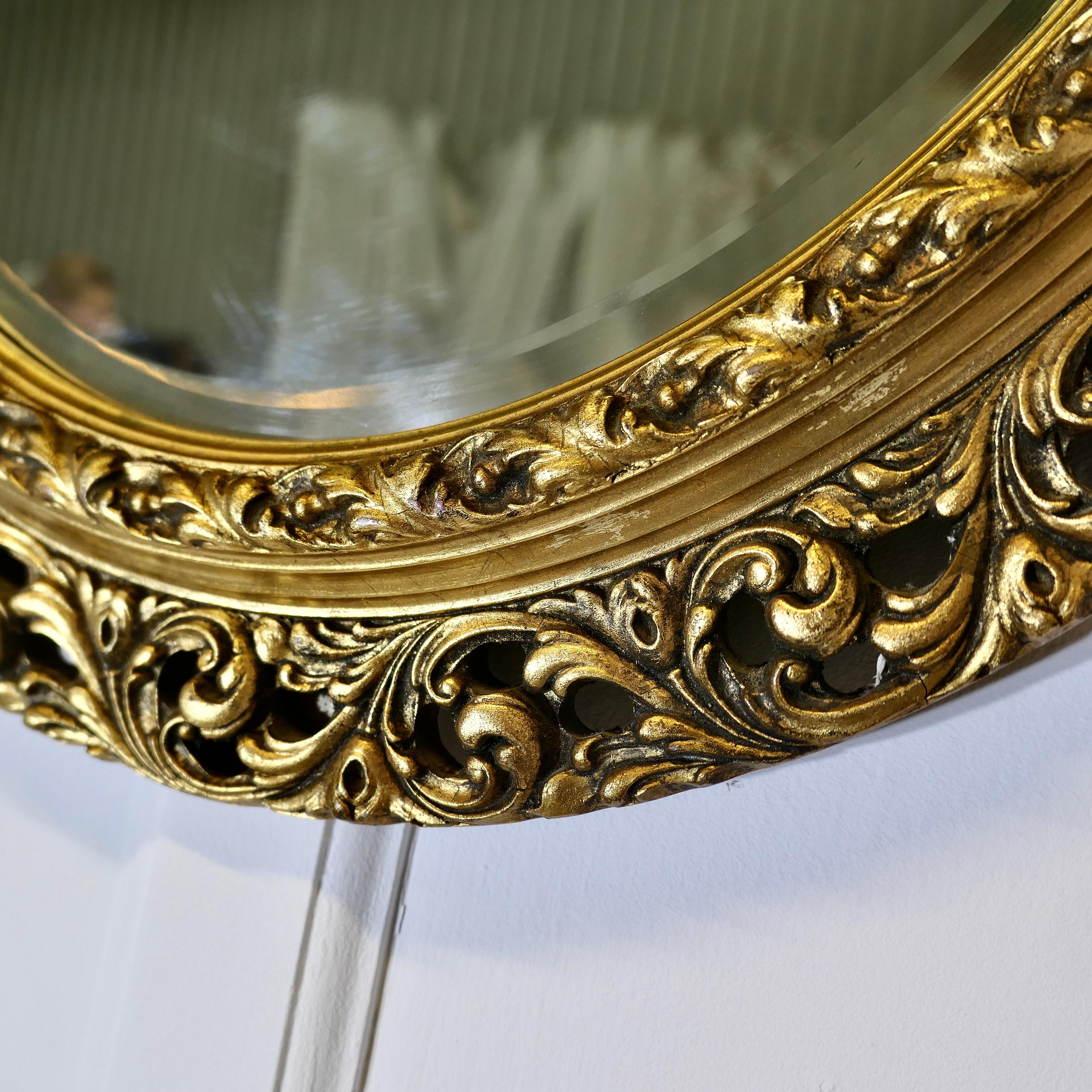 Miroir mural ovale sculpté et doré    C'est un miroir très attrayant en vente 1