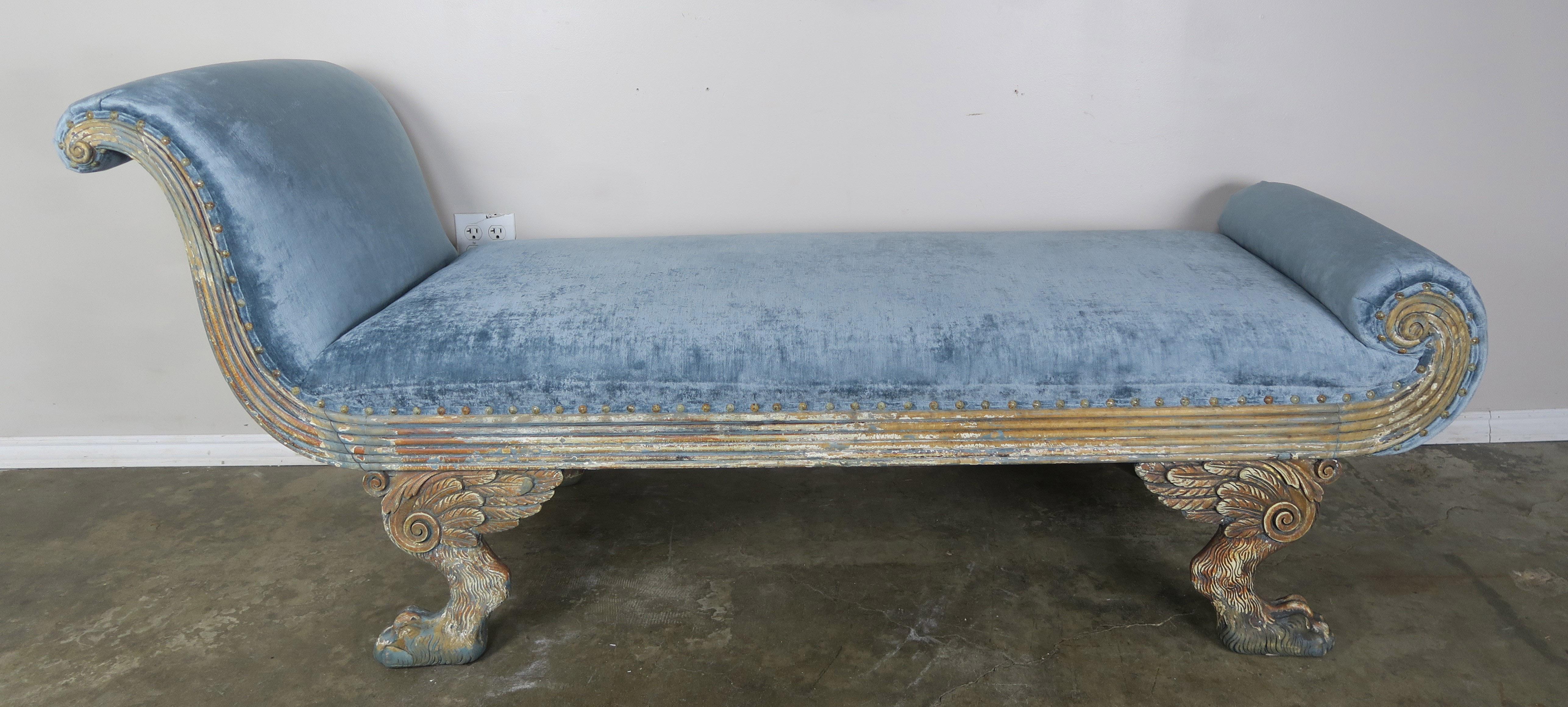 Carved wood painted chaise lounge that stands on four Duncan Phyfe style feet with winged lion's paws. The Chaise is newly upholstered in a blue linen velvet with self welt and nailhead trim detail.
Seat height 20