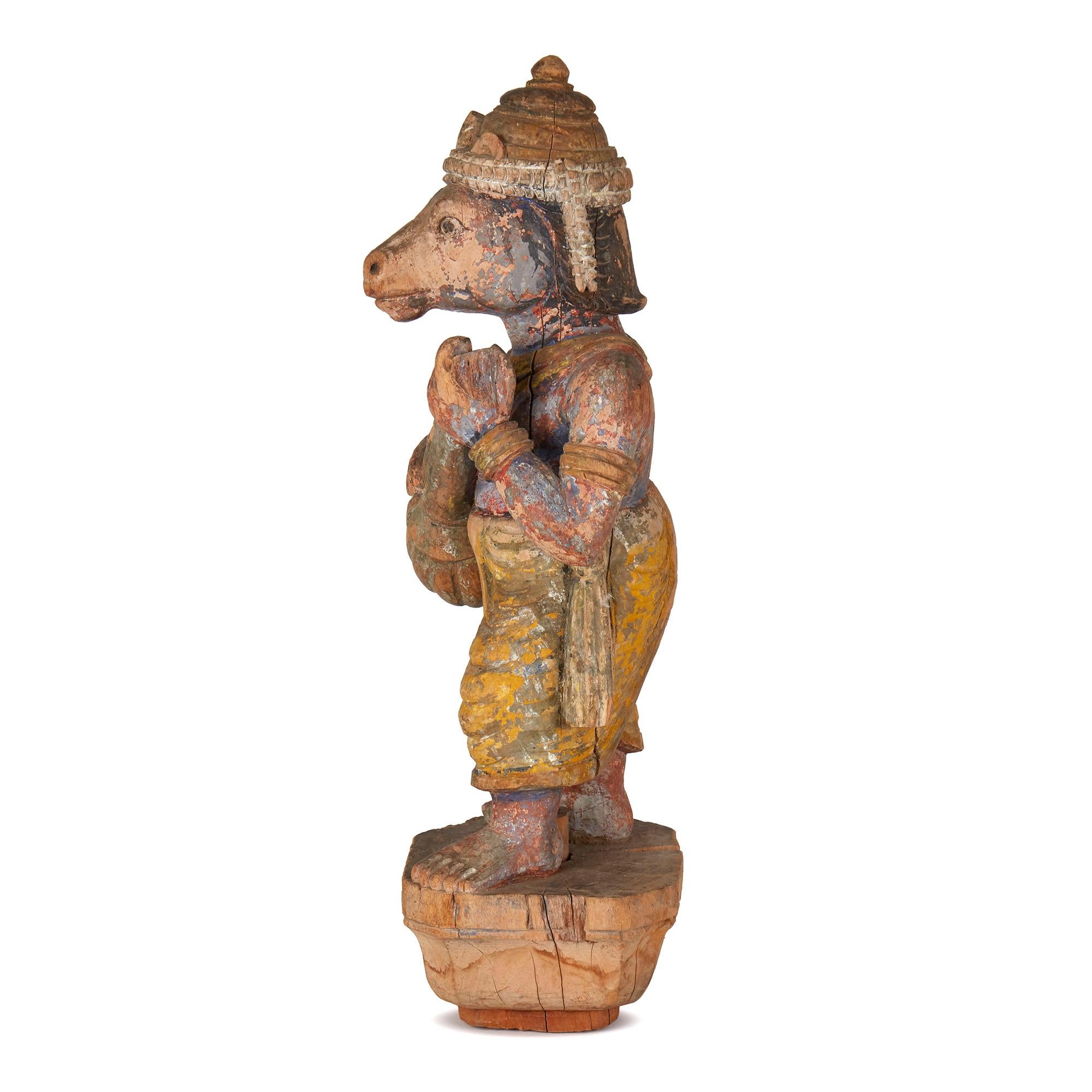 A Fine hand carved antique/vintage Indian wooden figure of an Indian deity with a horse's head and playing a lute like instrument. The figure believed to be a processional mount has original remnants of paint and is mounted on a chip carved wooden