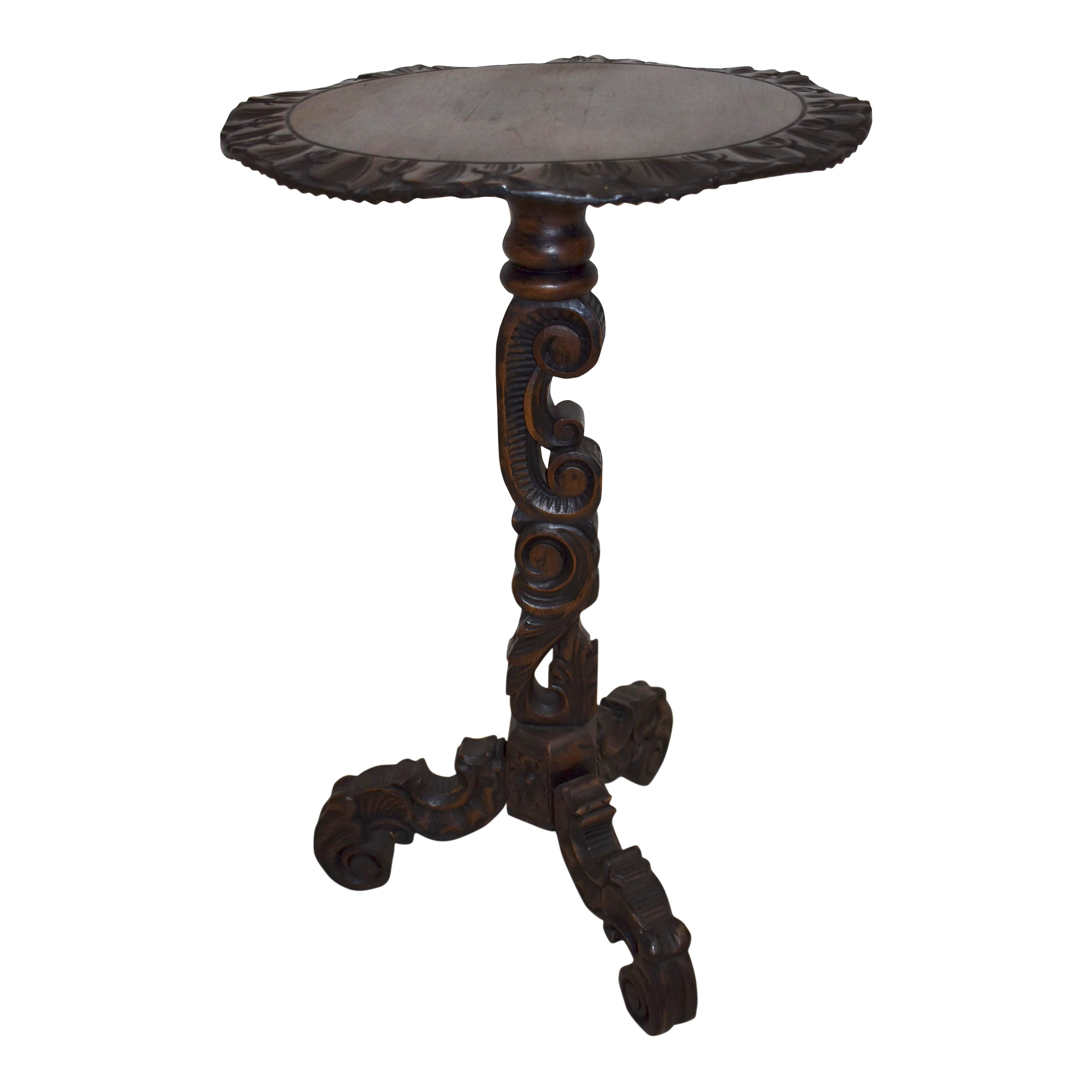 Impresionante desde todos los ángulos, esta mesa auxiliar intrincadamente tallada presenta un tablero redondo con borde ondulado, un pedestal único elaborado con una voluta en C tallada y follaje en volutas acorde con los muebles de estilo Luis XV,