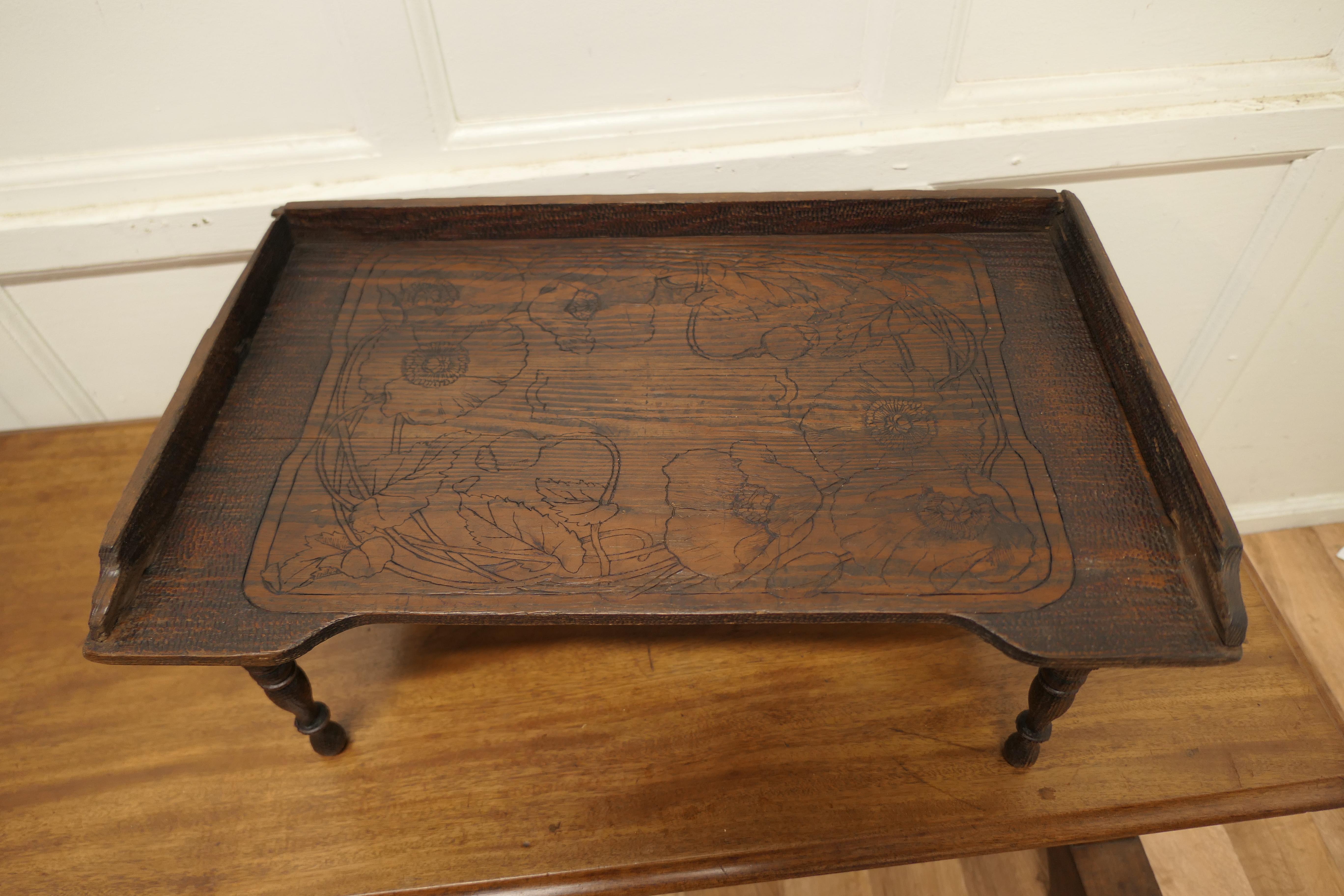 Carved pine breakfast bed tray table. 

This is a good Country Piece, it has a scratch carved decoration on the top.
It is a bed tray with foldaway legs which fold under and are held and released by a wooden spring.
Perfect for breakfast in bed
