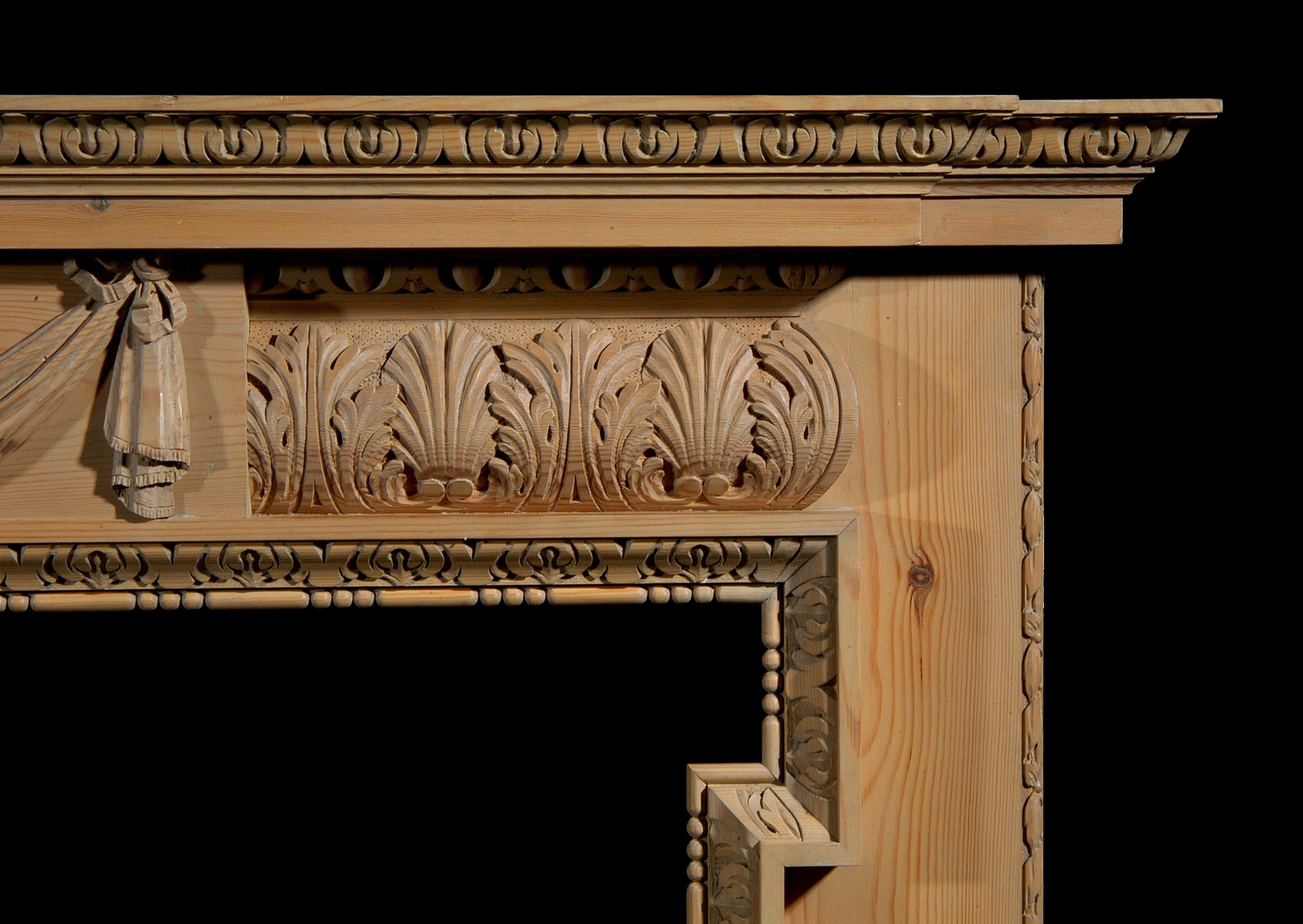 A carved pine fireplace with lion's mask and drapery to centre, barrel frieze with stiff acanthus leaf, egg and dart and leaf cornice mouldings and acanthus leaf inner leg moulding. 20th century. Copied from a George II original in Upper Brook