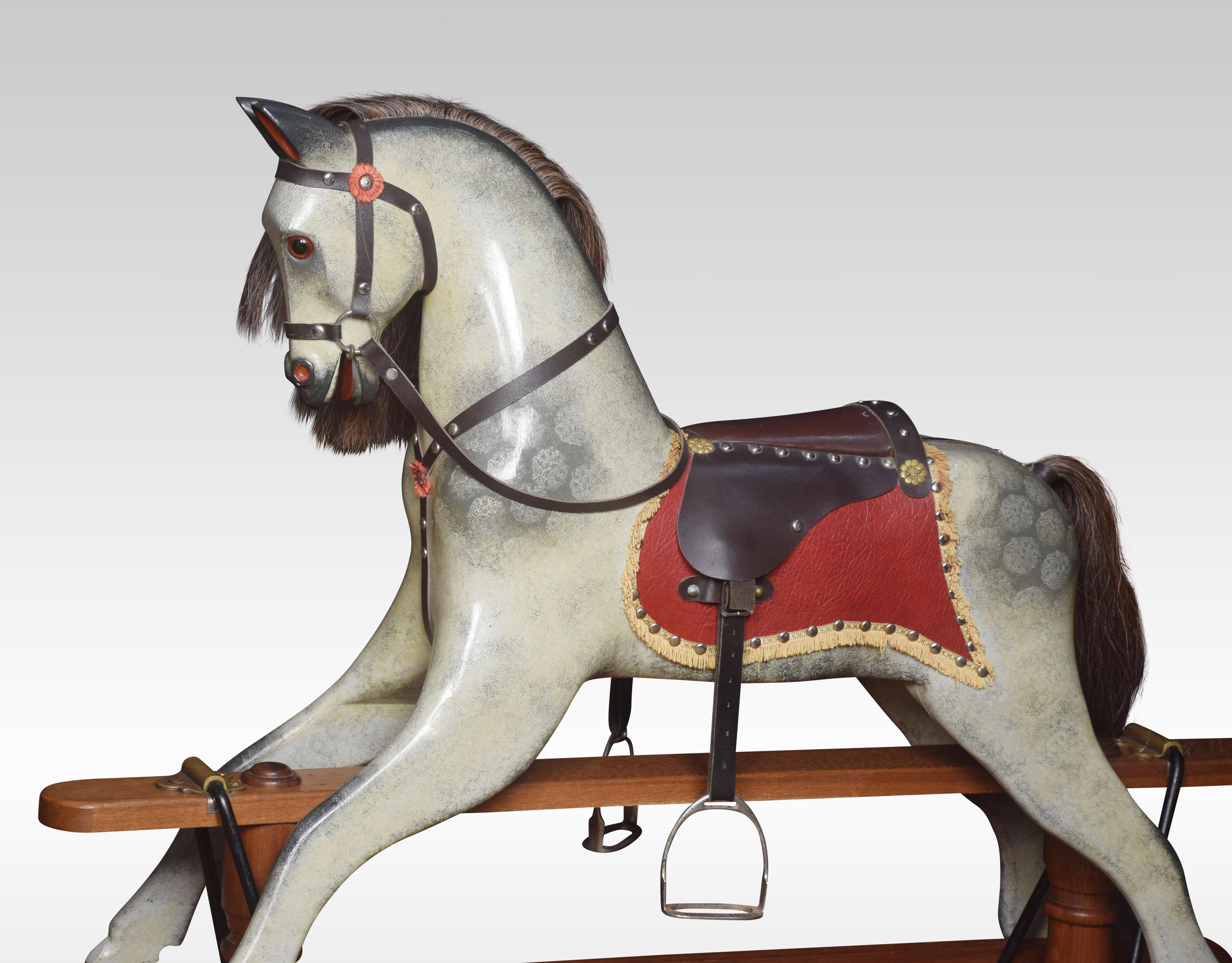 Carved and painted pine rocking horse with leather saddle and harness on trestle rocker.

Dimensions
Height 47 inches
Width 66 inches
Depth 19 inches.