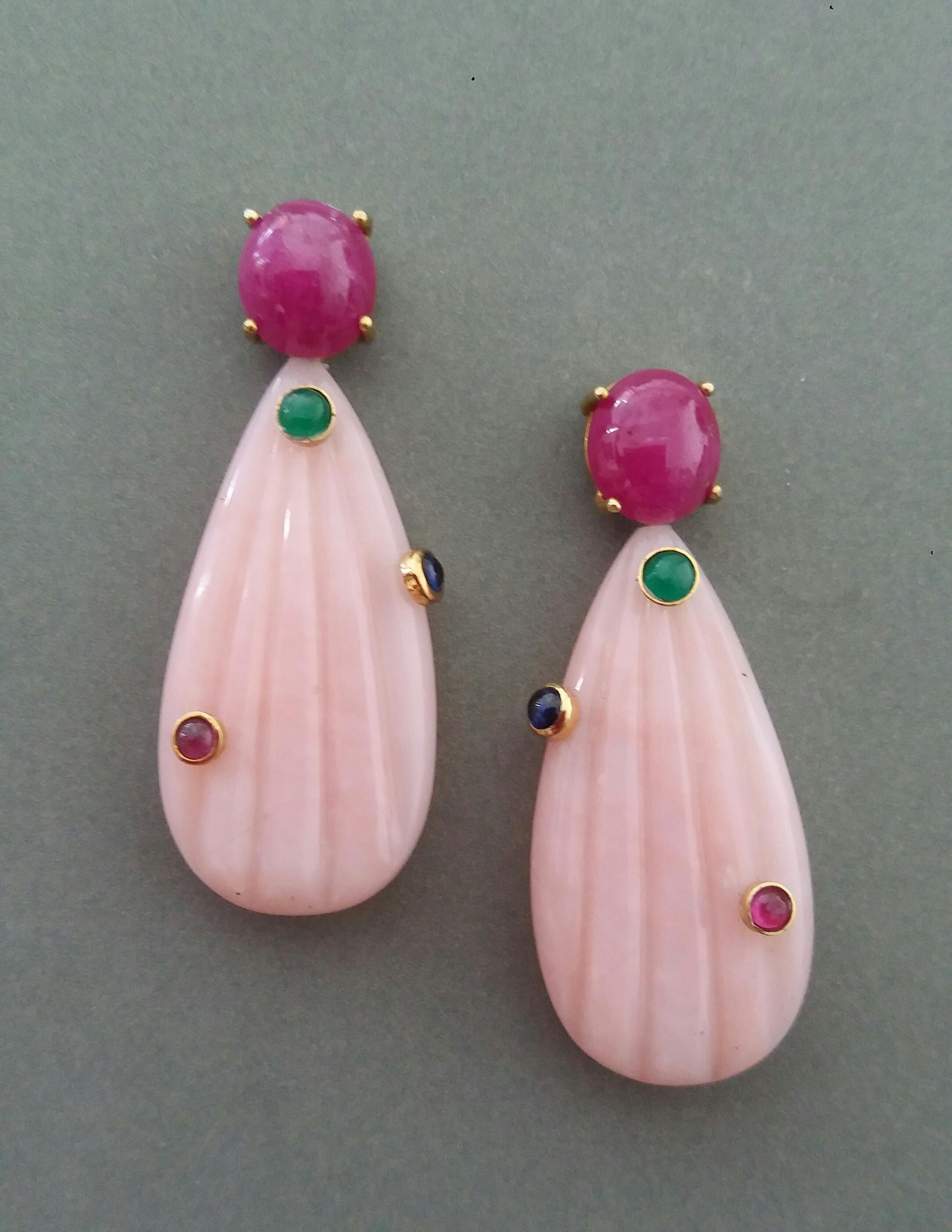 Unique earrings with a pair of Ruby  oval cabochon size 10 x 11 mm set in 14 kt solid yellow gold on the top and 6 small round ruby,blue sapphire and emerald cabochons set in 2 Pink Opal engraved flat drops measuring 20 x 40 mm. 

In 1978 our