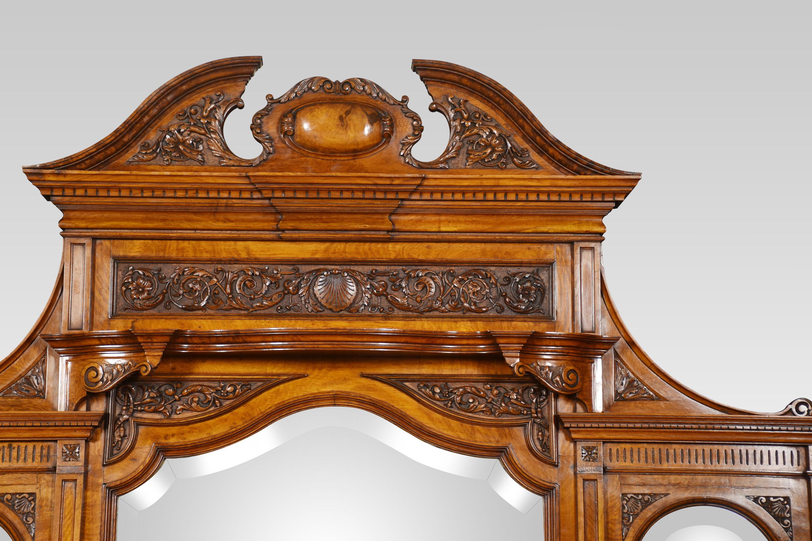 Carved pollard oak overmantel mirror, having a carved broken pediment over a frieze panel carved with acanthus scrolls and arabesques. The shaped shelf over a bevelled glass shield-shaped mirror flanked on either side with two arched mirrors,