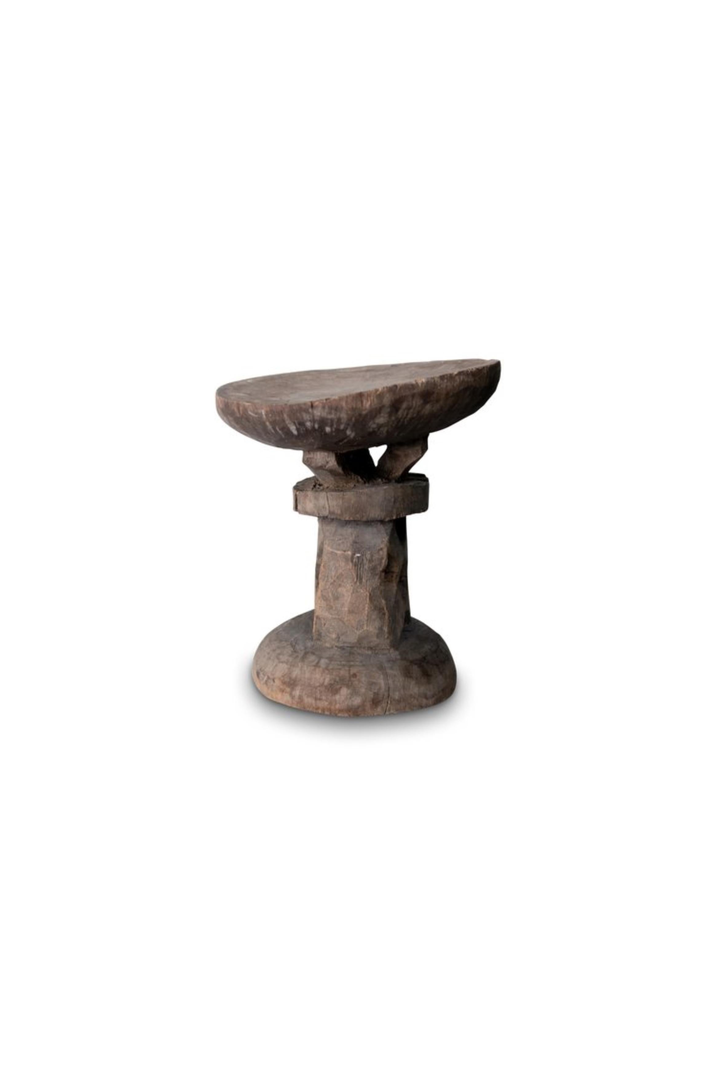 Ce tabouret en bois sculpté de style primitif du peuple Shona du Zimbabwe est une pièce de mobilier traditionnel originale. Le tabouret présente un siège rond soutenu par un pilier central ajouré, mettant en valeur le travail artisanal complexe