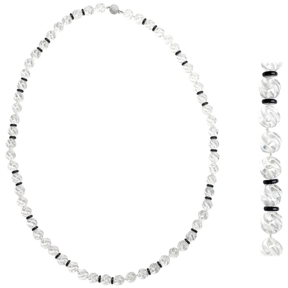 A carved rock crystal and black onyx rondelle bead necklace, sixty-one carved rock crystal beads measuring approximately 13-14mm each, separated by black onyx rondelle beads, in a repeating pattern, with an 18ct white gold pavé set diamond ball
