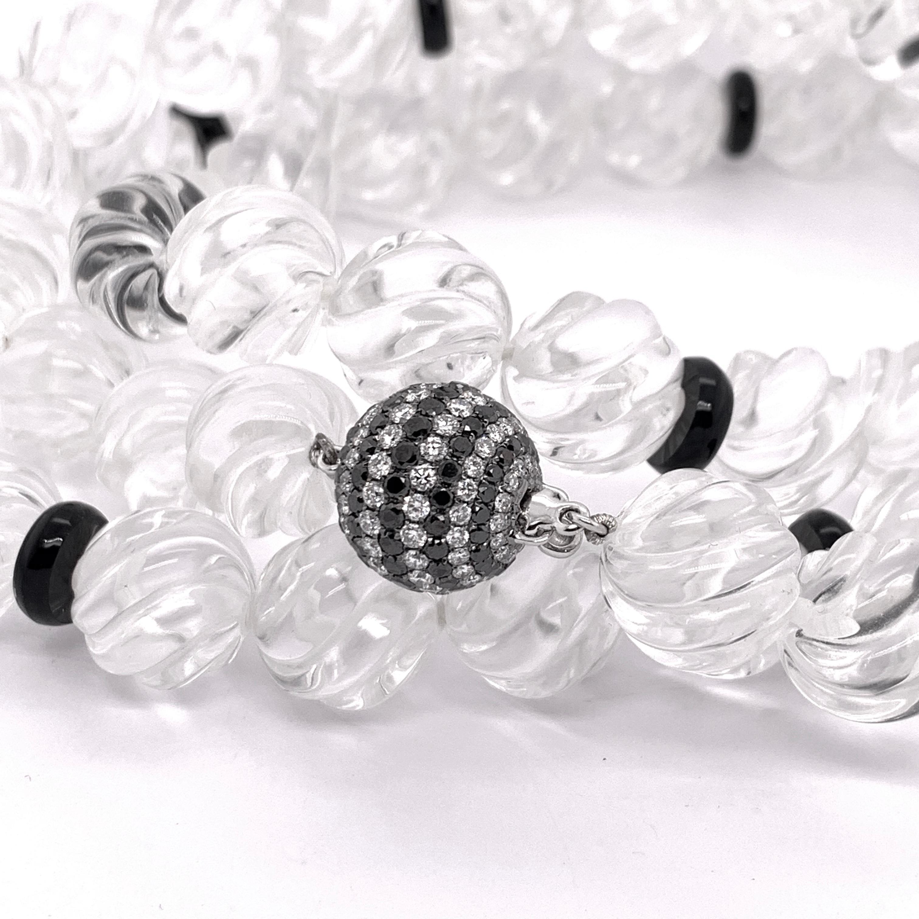 A carved rock crystal bead necklace, with black onyx rondelles, with an 18ct white gold pavé set black and white diamond ball clasp. Length approximately 33 inches.