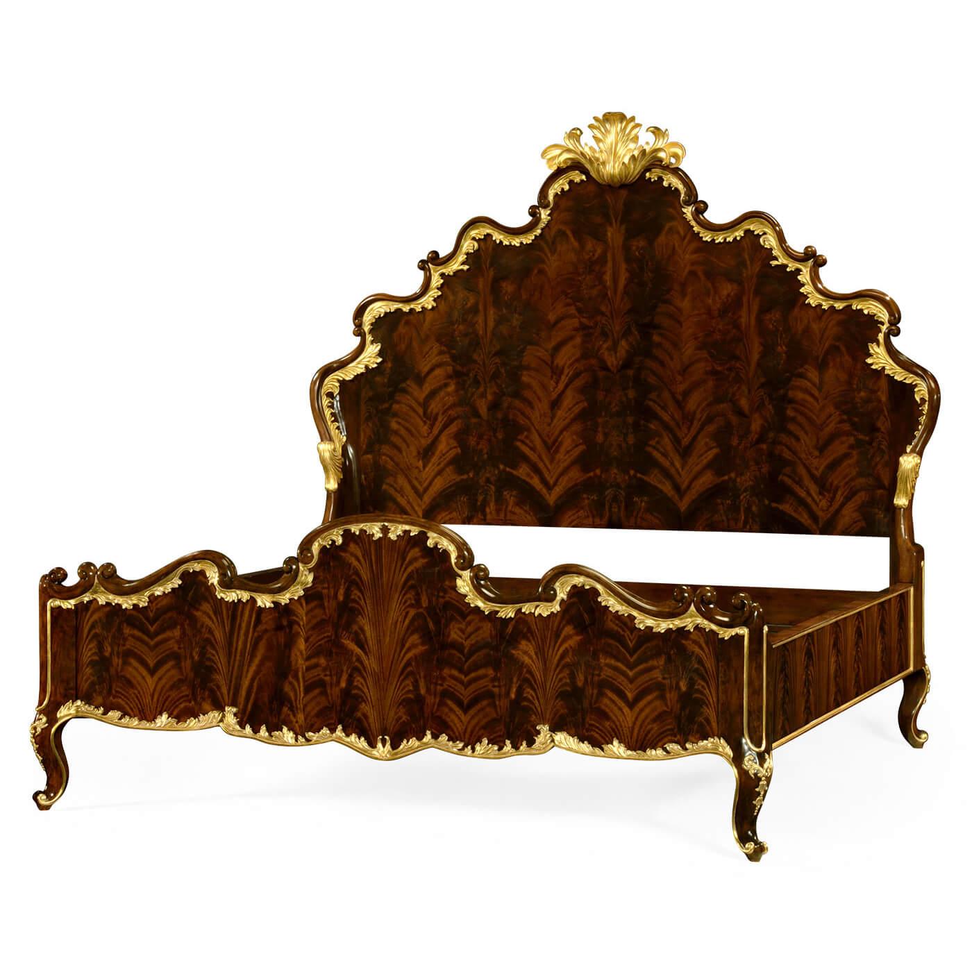A luxurious Rococo style antique bed in high lustre antique brown mahogany with flamed veneer, intricately carved head and footboard with ornate hand-carved gilded details along the edges, frame, and legs.

Dimensions: 88