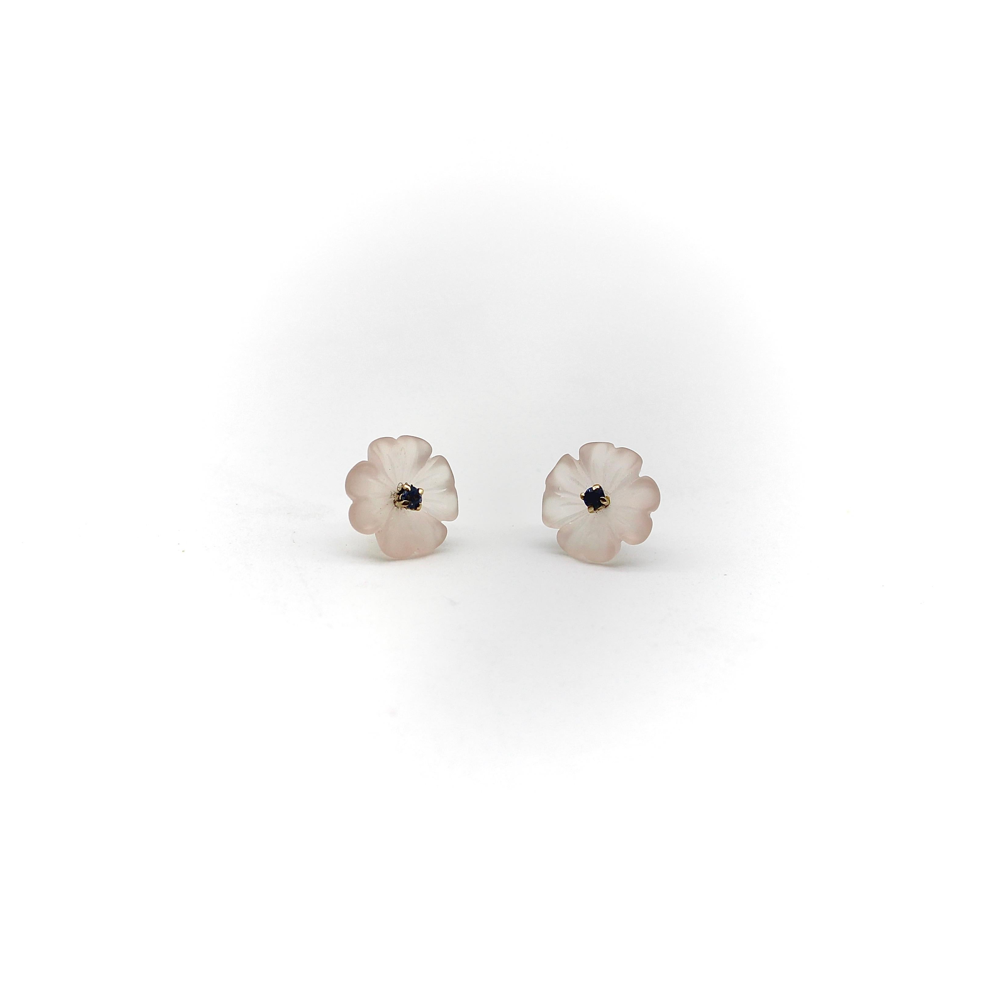 These 14k gold stud earrings feature beautiful hand carved rose quartz in the shape of a flower. The flower has four petals that undulate when viewed from the side, and contain a tiny blue sapphire prong-set as the flower’s piston. The rose quartz