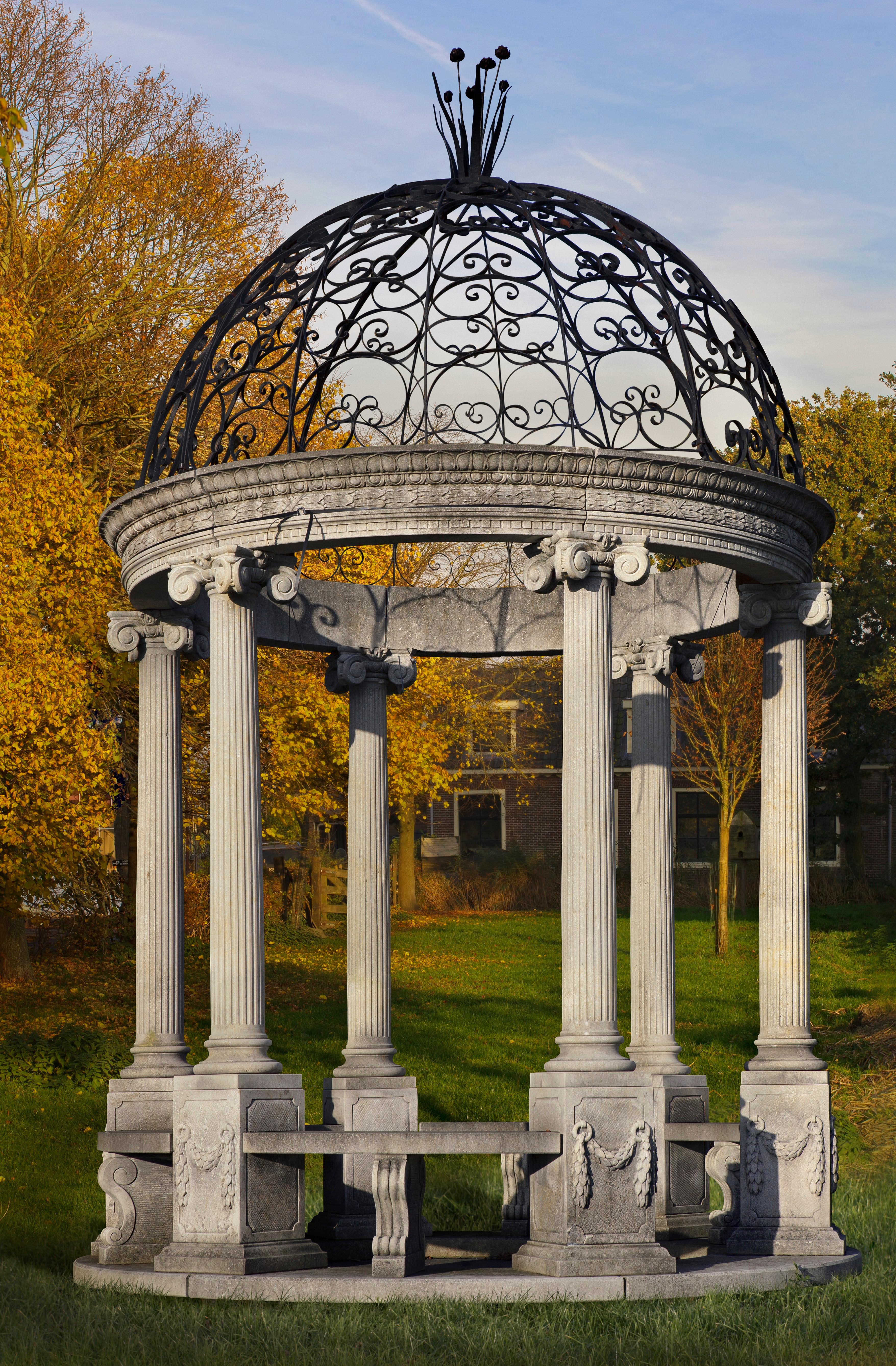 Rotonda ou gloriette de jardin en pierre calcaire sculptée de style classique avec un plateau en fer forgé. Fabriqué au début du 20e siècle. La Rotonda comporte six colonnes entre lesquelles se trouvent des bancs. Les piliers sont sculptés dans un