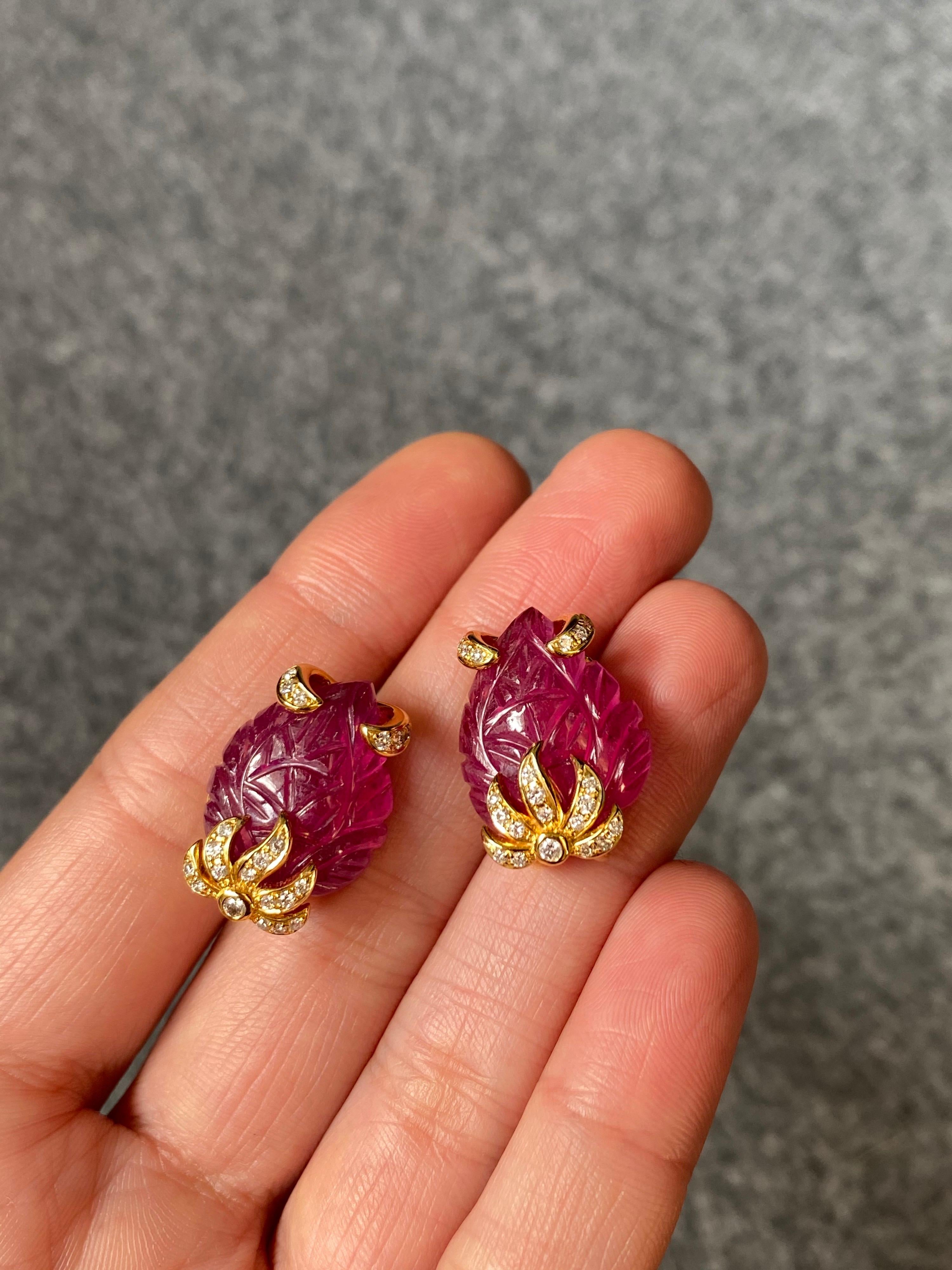 A pair of beautifully carved 21.14 carat Rubies with 0.3 carat Diamonds, set in solid 18K Yellow Gold. The intricately carved rubies make the earrings very unique, giving them an art-deco look. 
The earrings come with a push-pull backing. 
Free