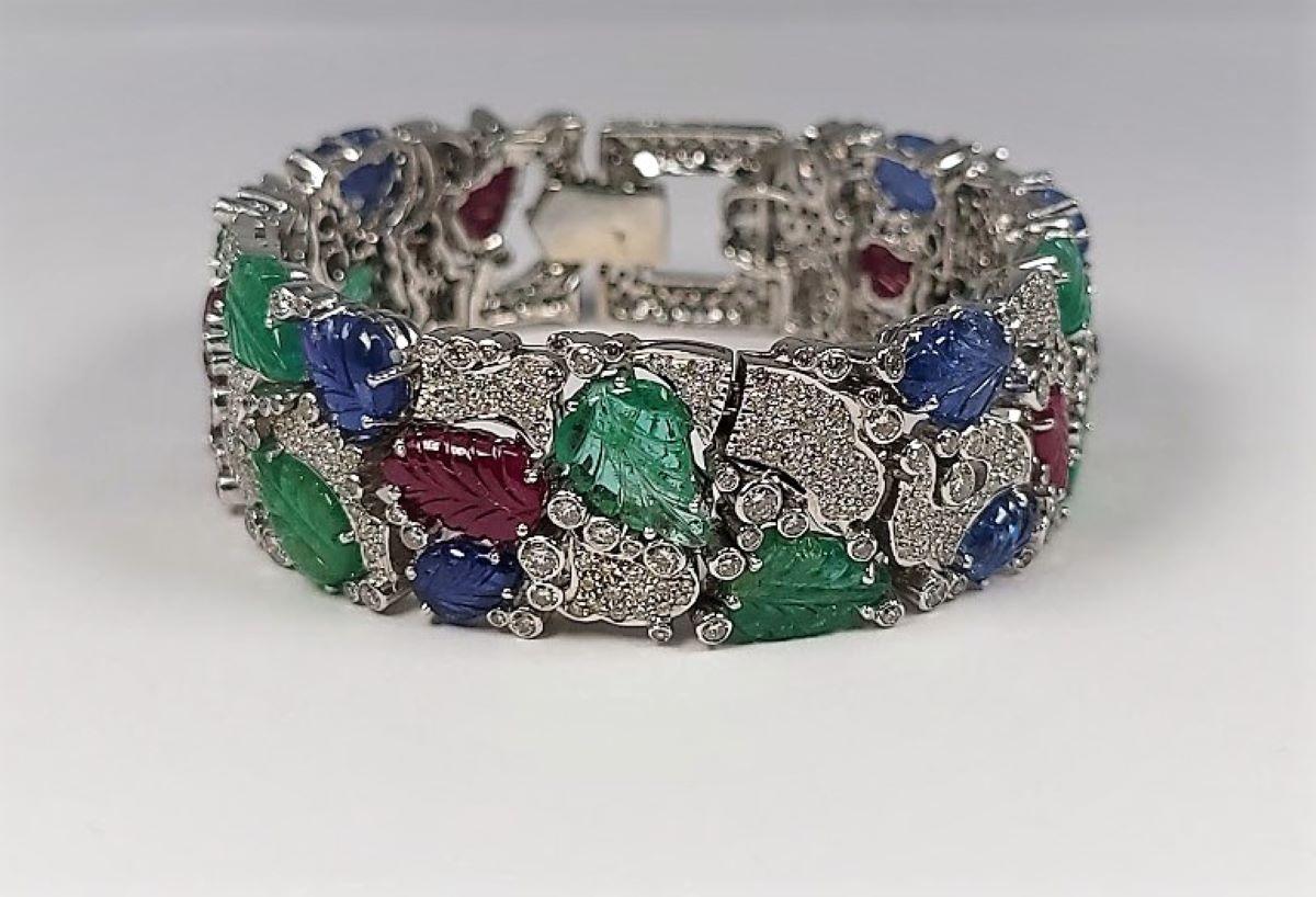 Unterstützt schöne geschnitzte Smaragde, Rubine und blaue Saphire, die alle mit 11,00 Karat runden Diamanten akzentuiert sind.  