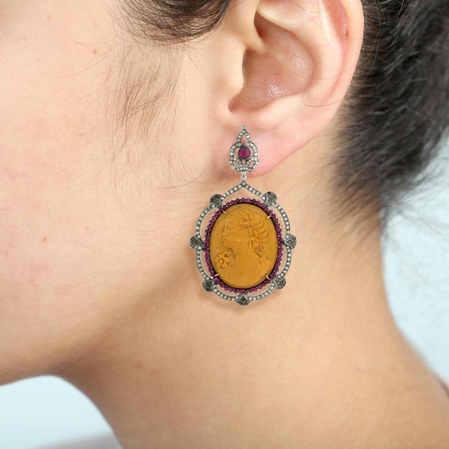Preciosos pendientes colgantes de camafeo de concha con la cara tallada, acentuados con rubíes y diamantes, elaborados en oro de 18k. Un accesorio atemporal y sofisticado

18k:1.71g,
Diamond:3.35ct,
Silver:25.89gm,
Rubí: 0,96 ct,
Cameo-85.05
Tamaño: