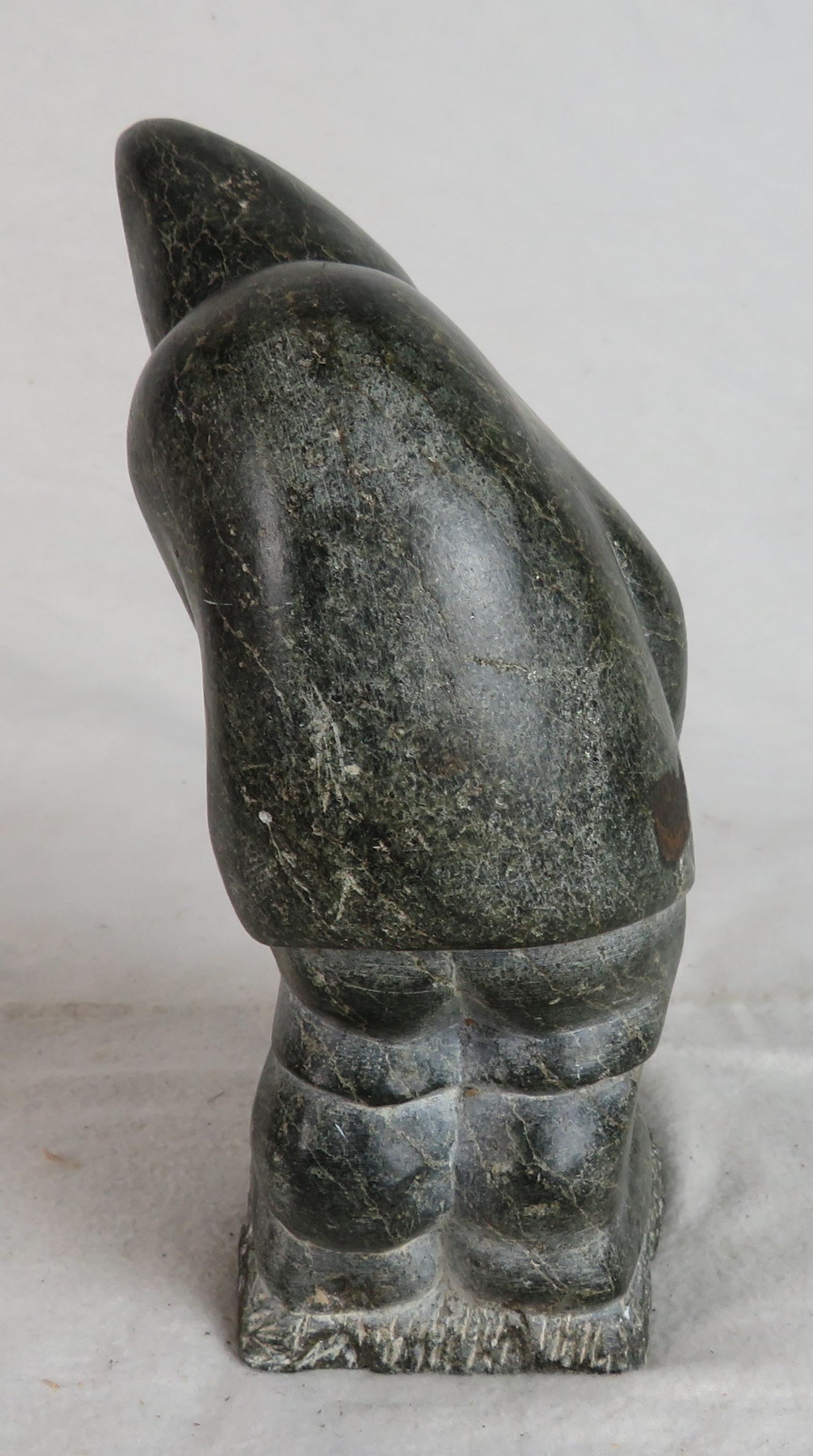 Hand-Carved Carved Soapstone Sculpture of an Inuit Leaning Forward, Holding Bag at Feet For Sale