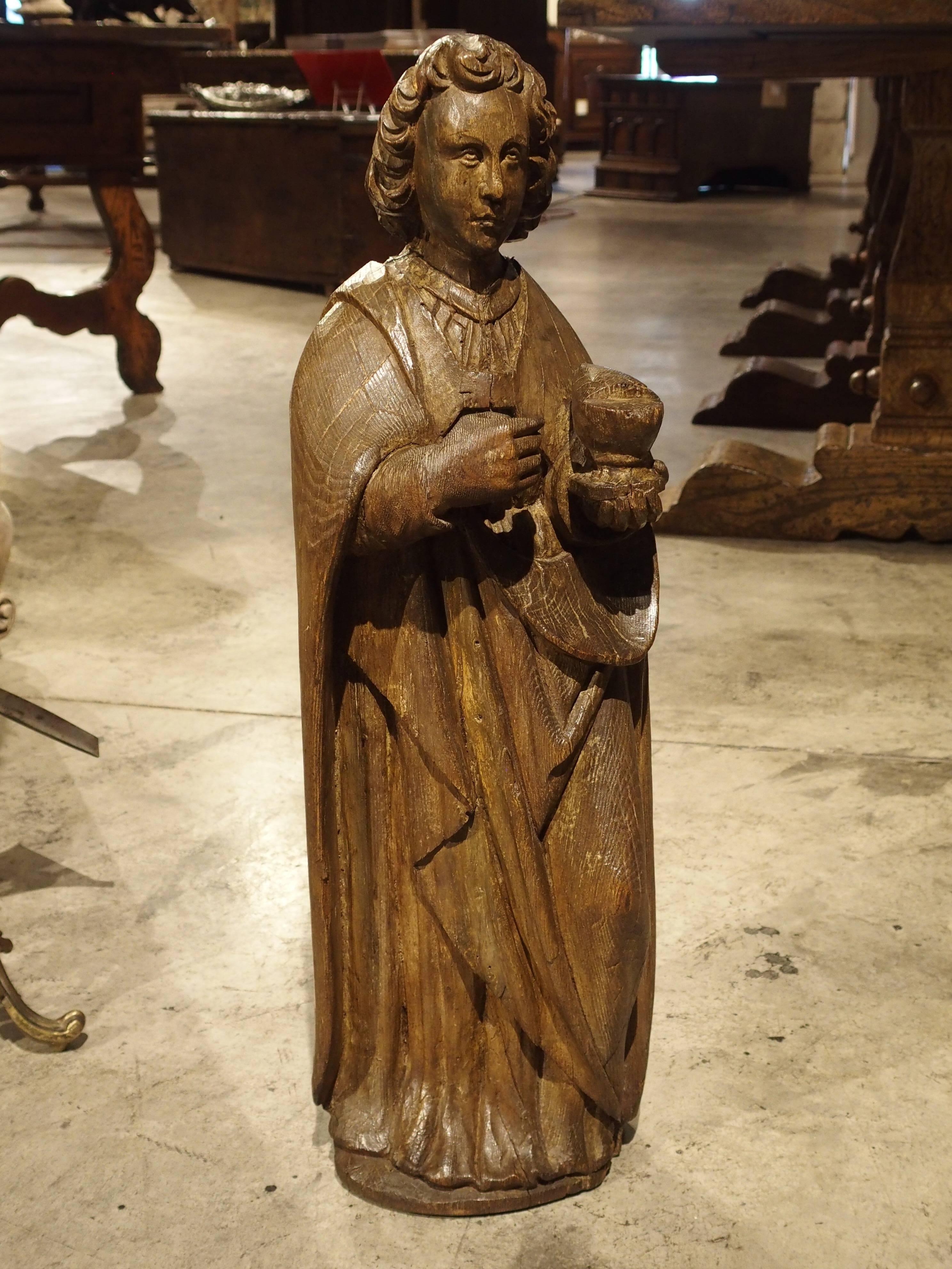This beautifully hand-carved oak figure represents St John The Evangelist. Probably from Germany, this saint wears a long, draped robe and is holding a chalice in his left hand. Saint John is often depicted with a chalice. It is a reference the