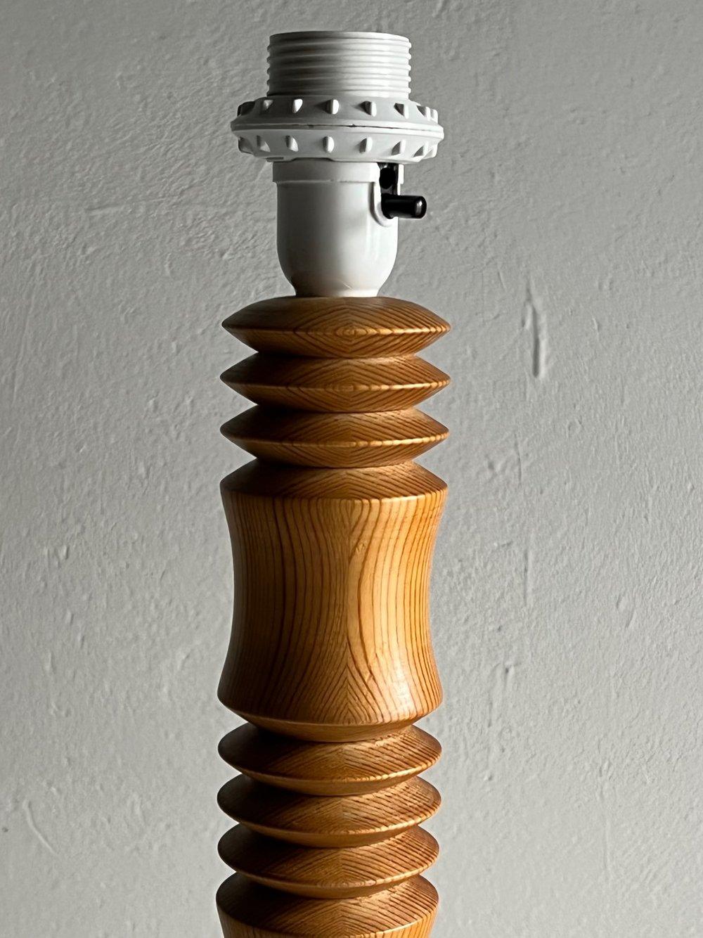 Lampadaire minimaliste au design sculpté en bois de pin massif. Livré sans abat-jour.