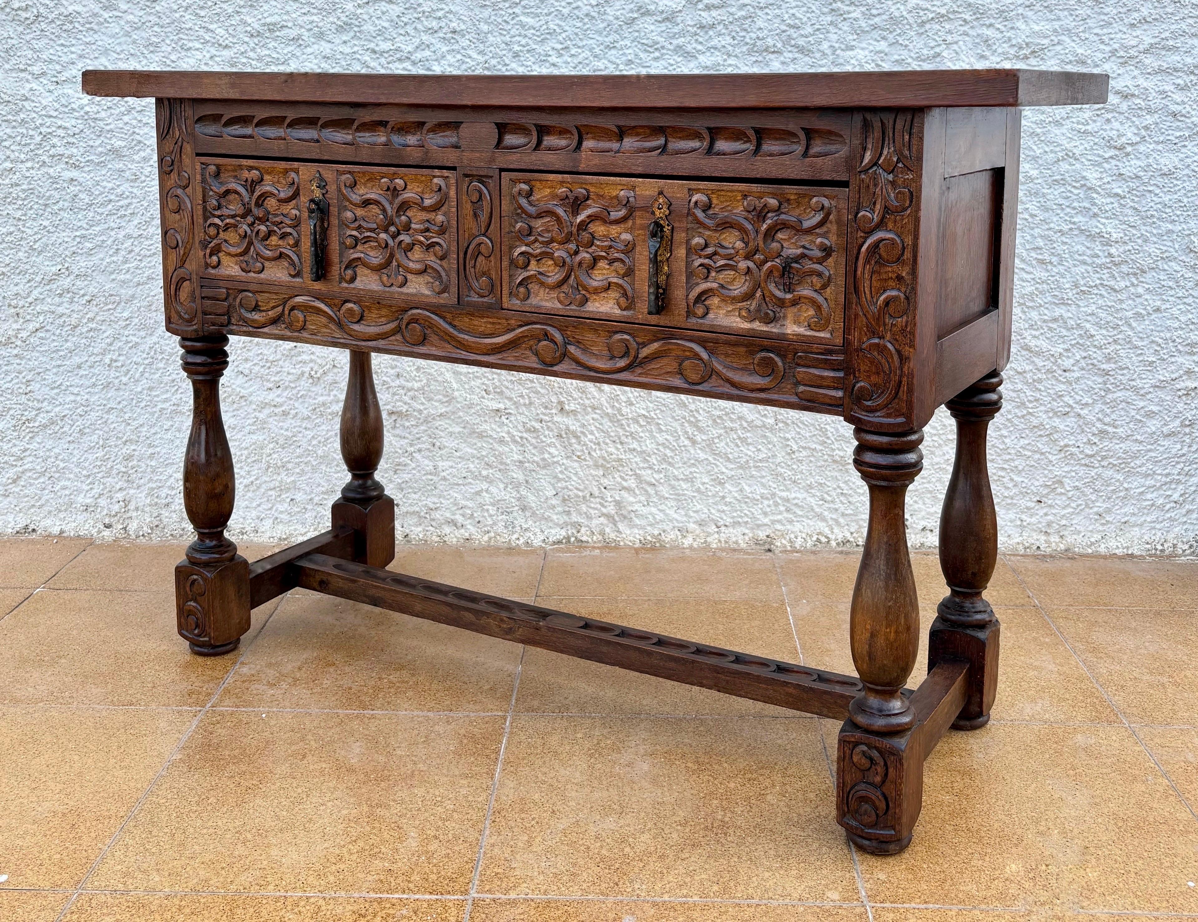 Beautiful antique carved oak console in the Spanish Renaissance Revival style, full of charm and decorative character. The front showcases detailed hand-carved panels with elegant foliage motifs, adding depth, texture and authenticity. With two