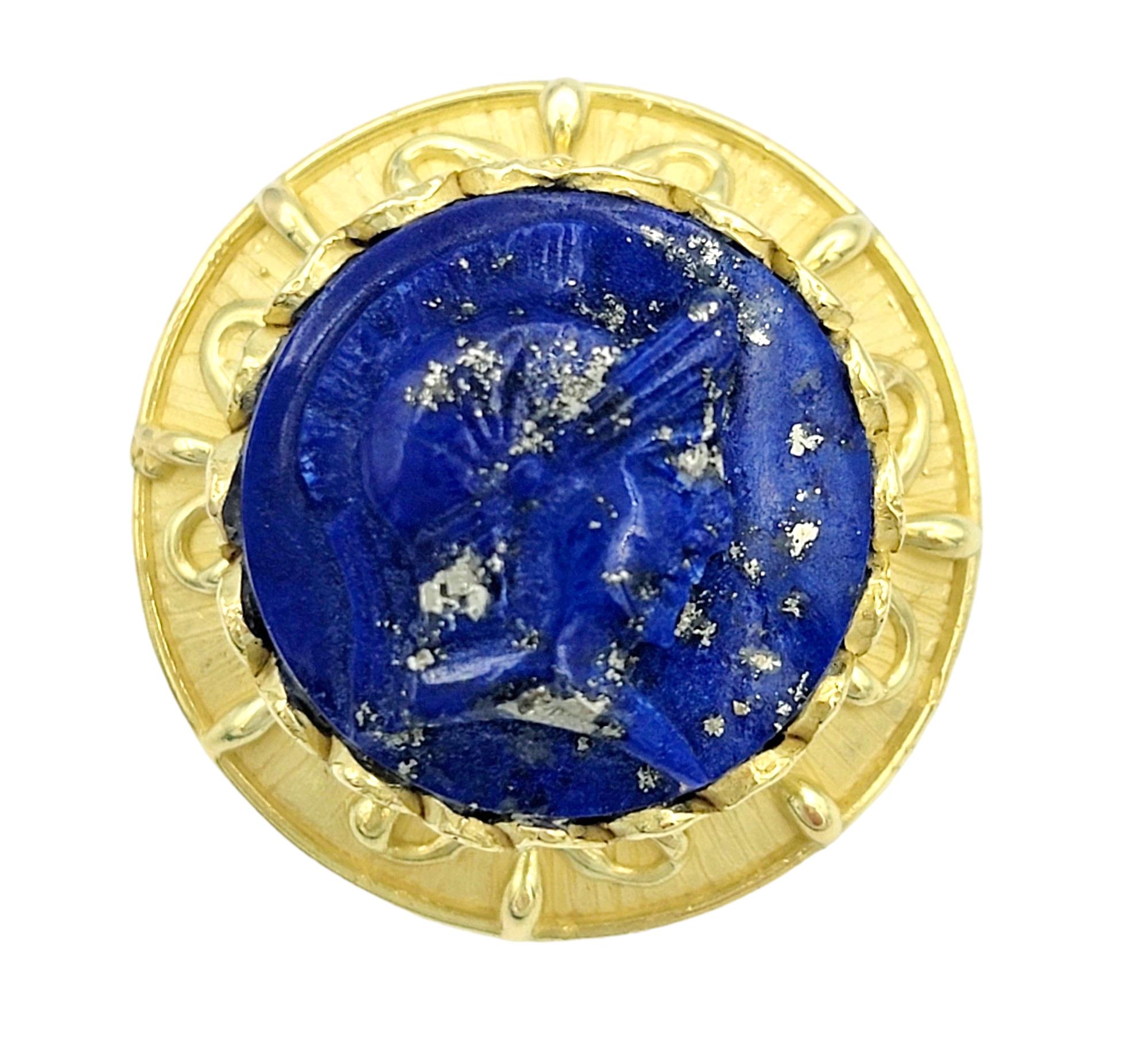 These striking stud earrings, set in radiant 18 karat yellow gold, are a testament to artistic craftsmanship and unique design. At their center, each earring features a lapis lazuli stone bearing a finely carved image of a Spartan warrior. The
