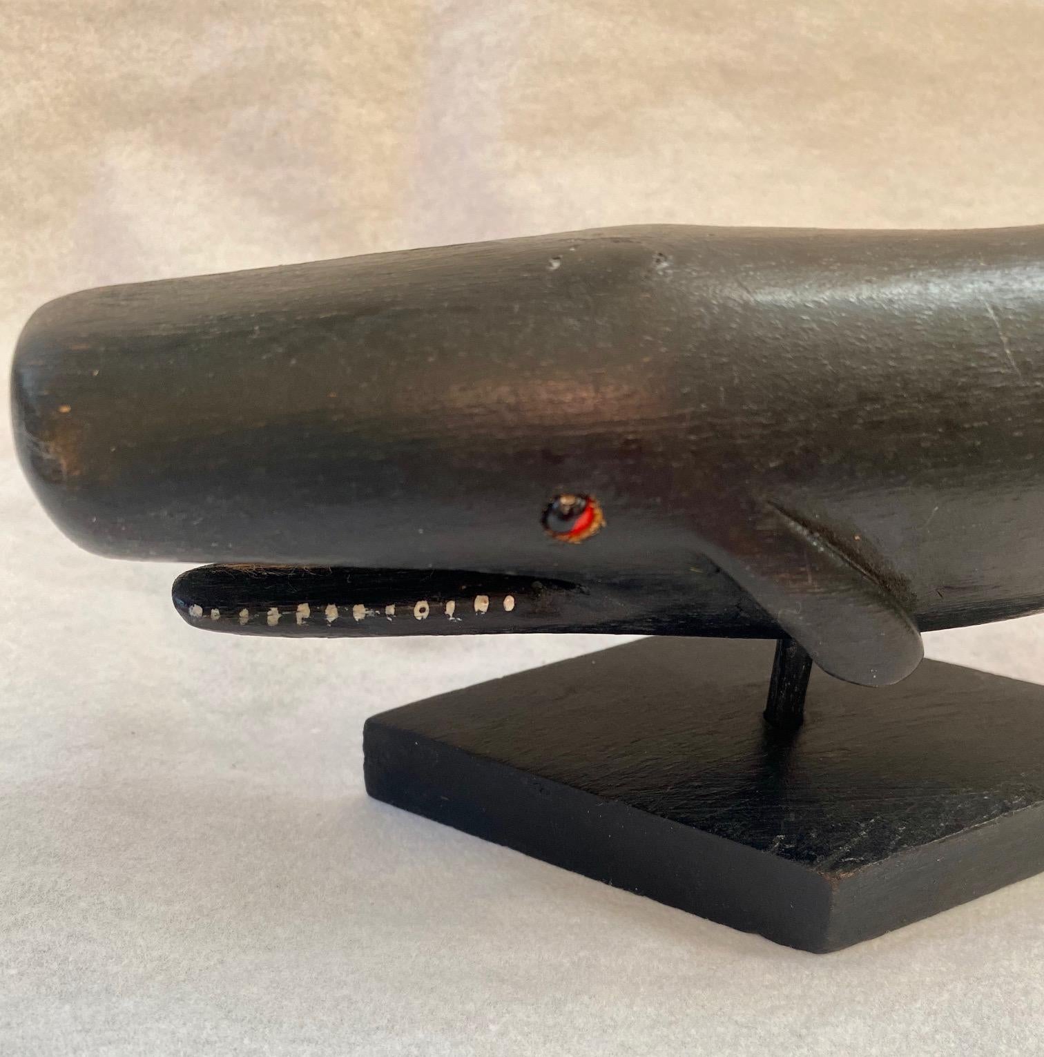 Vintage carved and painted sperm whale, by Willard Shepard (1912-1965), a beautifully carved-in-the-round small whale with deep carved red painted eyes, bas relief pectoral fins, tail posed at canted angle, and open mouth to expose painted teeth,