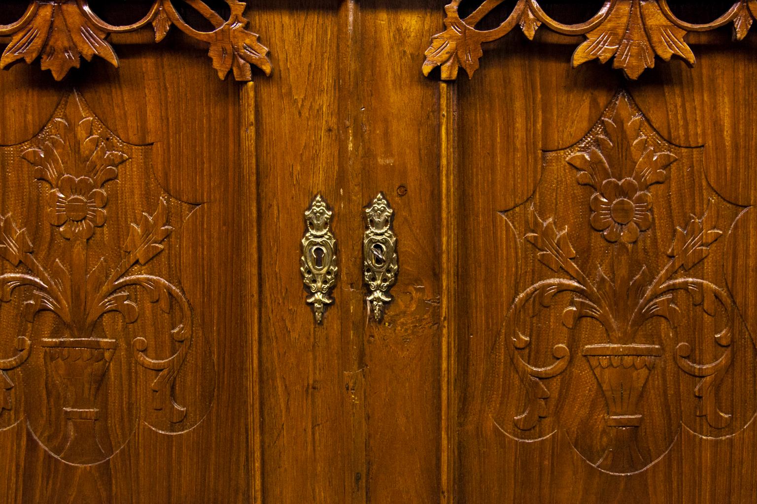 Armoire à portes vitrées sculptées en spirale, avec des feuilles et des vignes sculptées dans le fronton et la frise ; des appliques florales sculptées sur les portes supérieure et inférieure, un seul tiroir avec des feuillages sculptés ; des