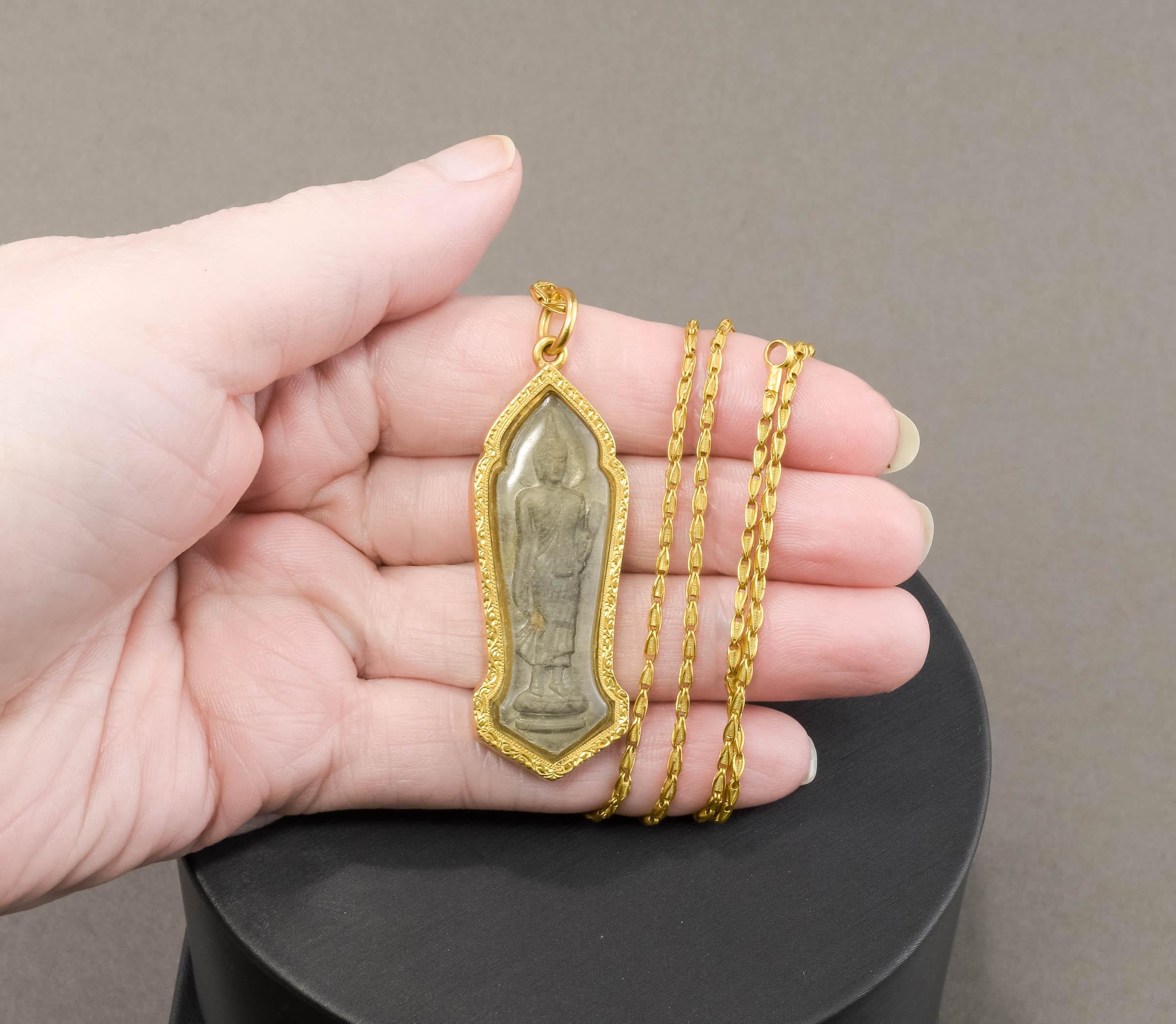 Offered is a particularly beautiful carved stone Buddha under glass, within a decorative high karat gold frame - suspended from a fancy link high karat gold chain.  The research I have done tells me that this amulet or reliquary is based on a