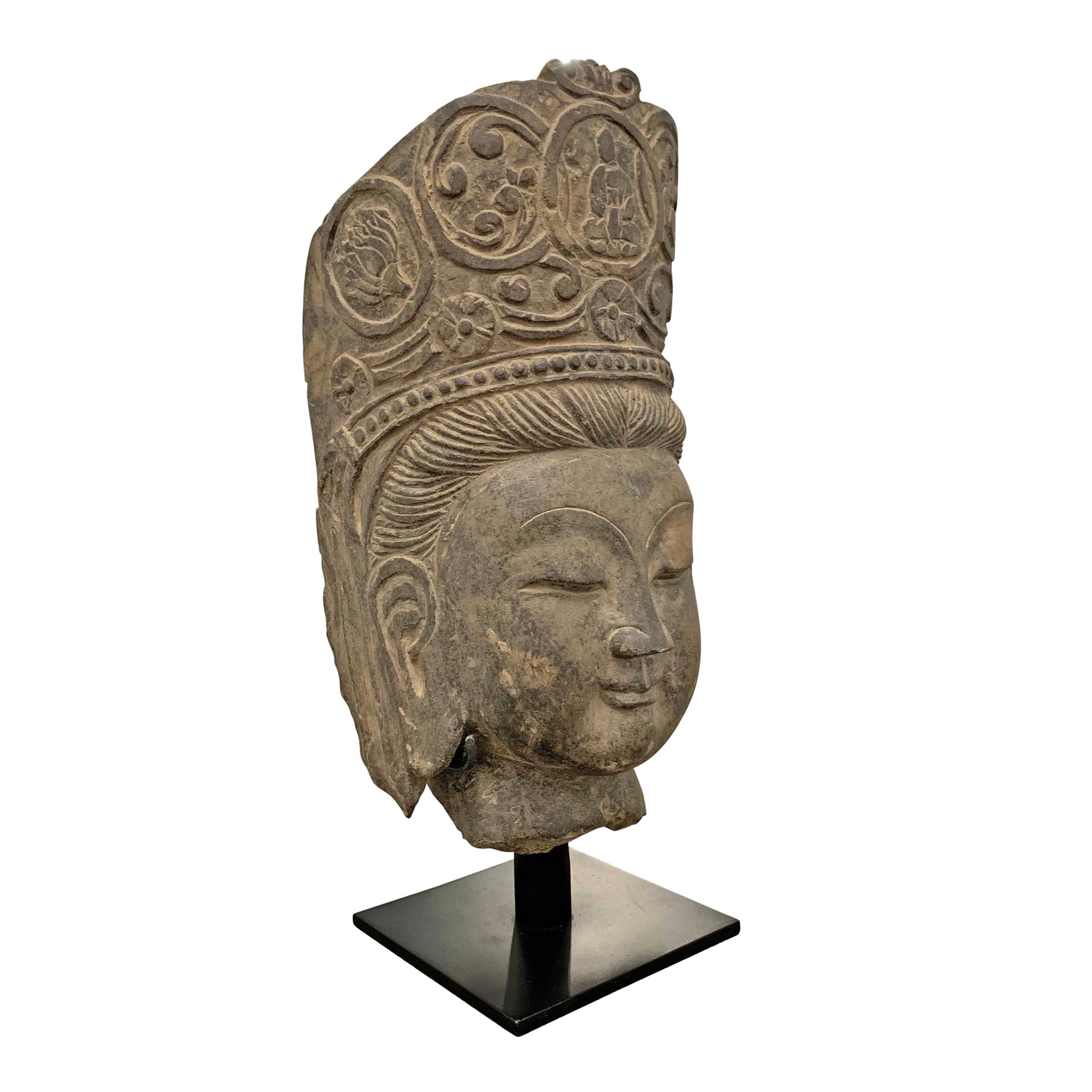 A serene carved limestone Guanyin head with a compassionate expression, on a custom steel mount. In Buddhism, Guanyin is widely considered to be the Goddess of Mercy and compassion.