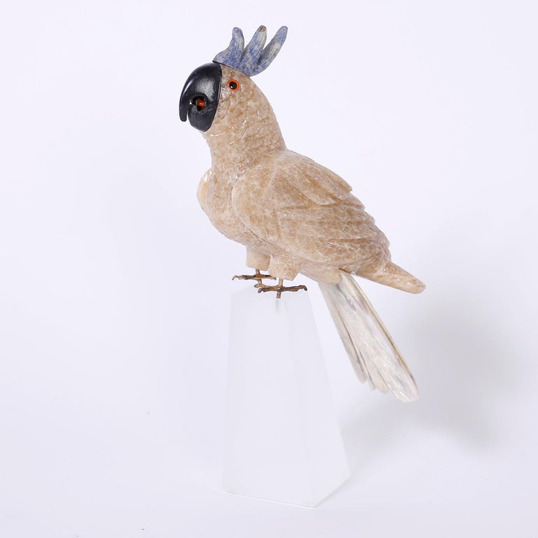 Parrot sculpture hand carved from exotic semi-precious stones with brass feet and perched on a frosted Lucite base.