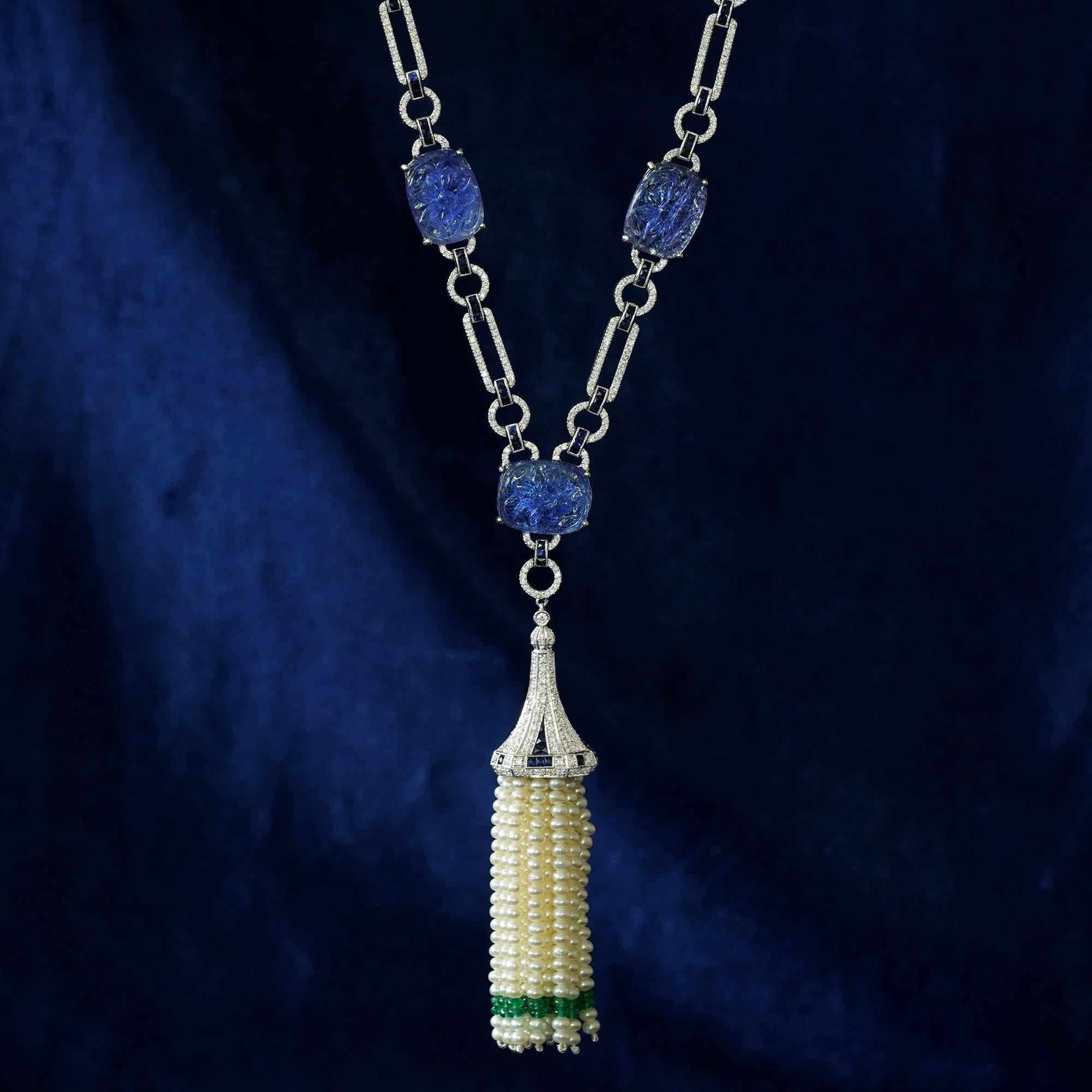 This beautiful necklace features freshwater pearls and bead emerald that hold a gorgeous tassel. Tassel charm is made of diamonds and French cut sapphires, beautifully hanging from cushion-cut tanzanite’s, hand carved with flower design. All are
