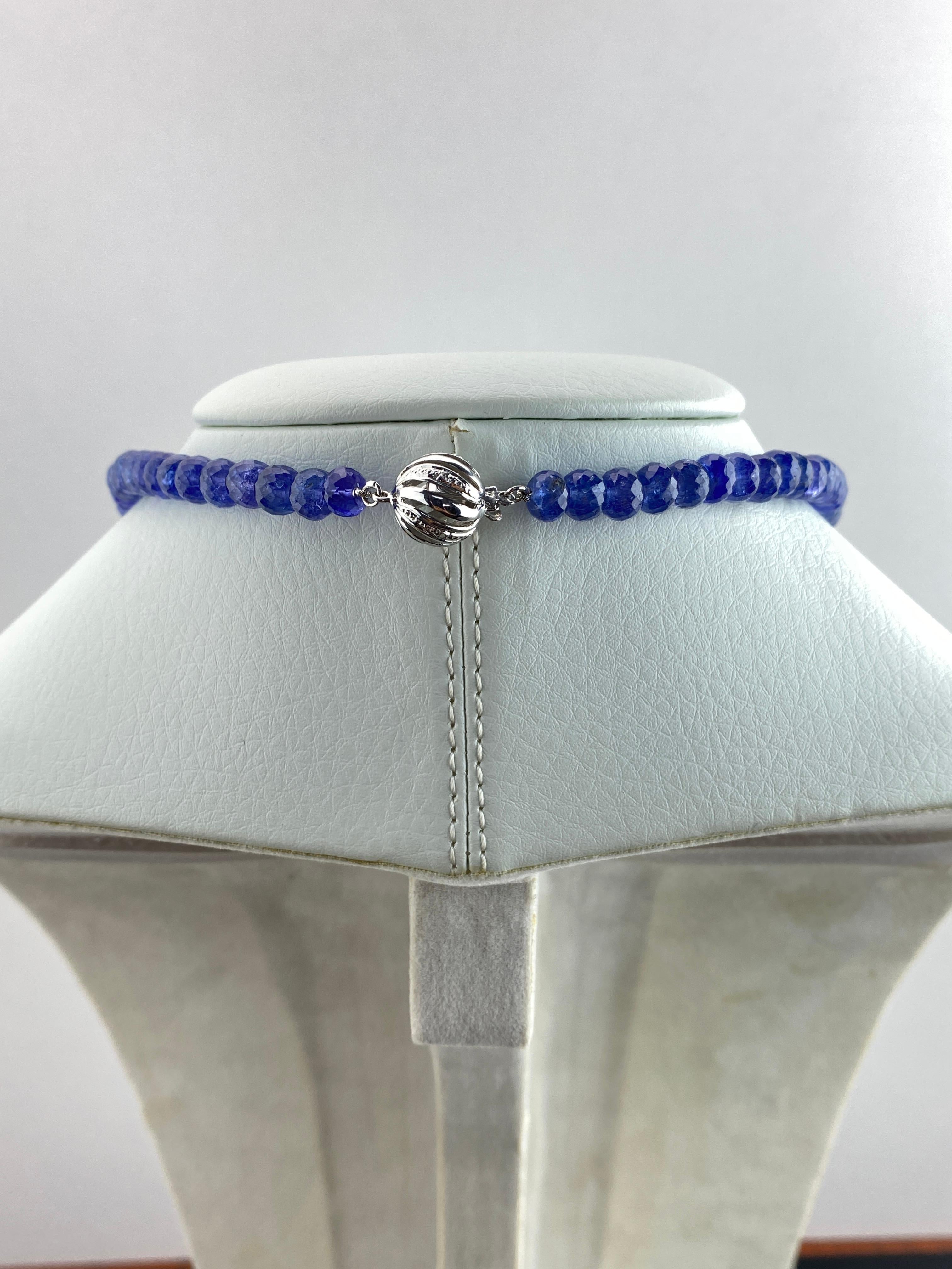 Una collana di perline dall'aspetto art-decò unica nel suo genere, con un ciondolo di tanzanite intagliata da 45,57 carati (18X25 mm), ornato da diamanti incastonati in oro bianco massiccio 18 carati. Il centro è uno smeraldo naturale dello Zambia