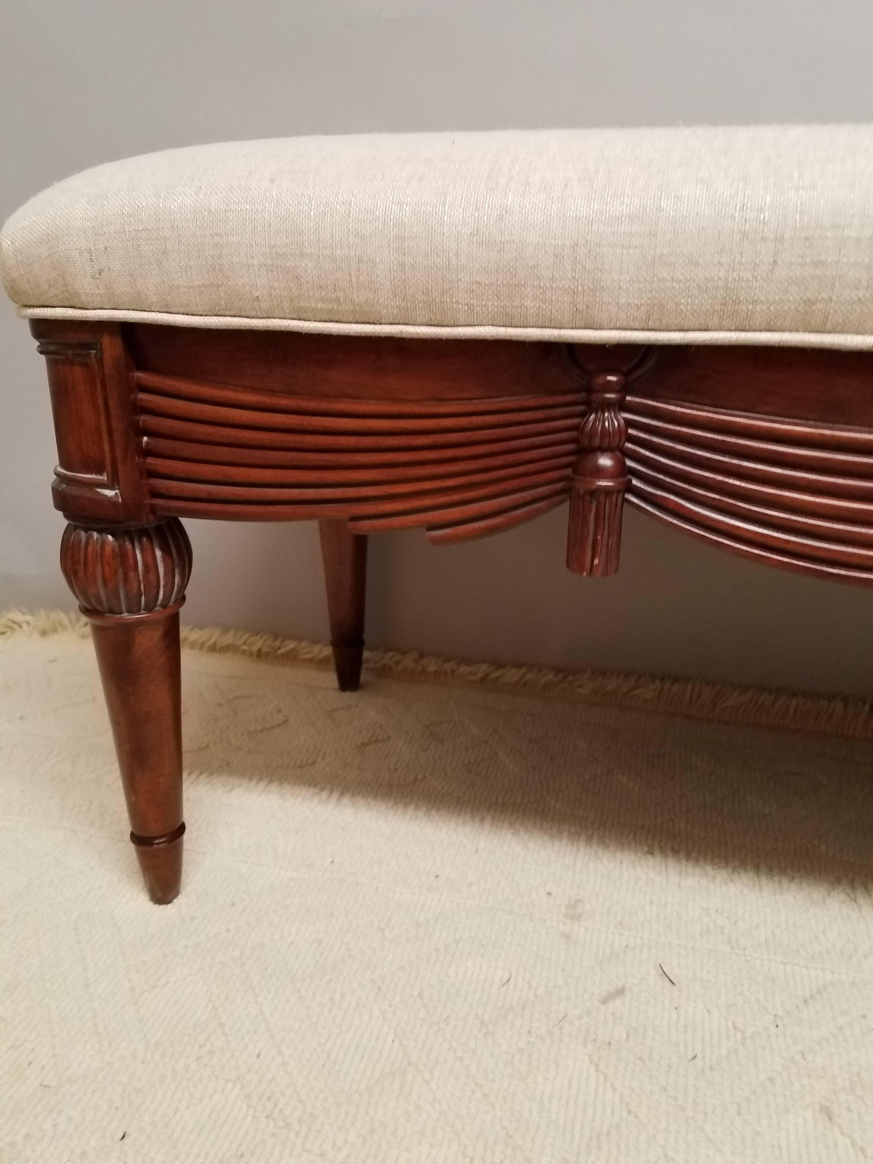 A neoclassical carved bench. Newly upholstered in oatmeal linen this bench has a wonderful swag and tassel carved apron resting on trumpet legs.


 