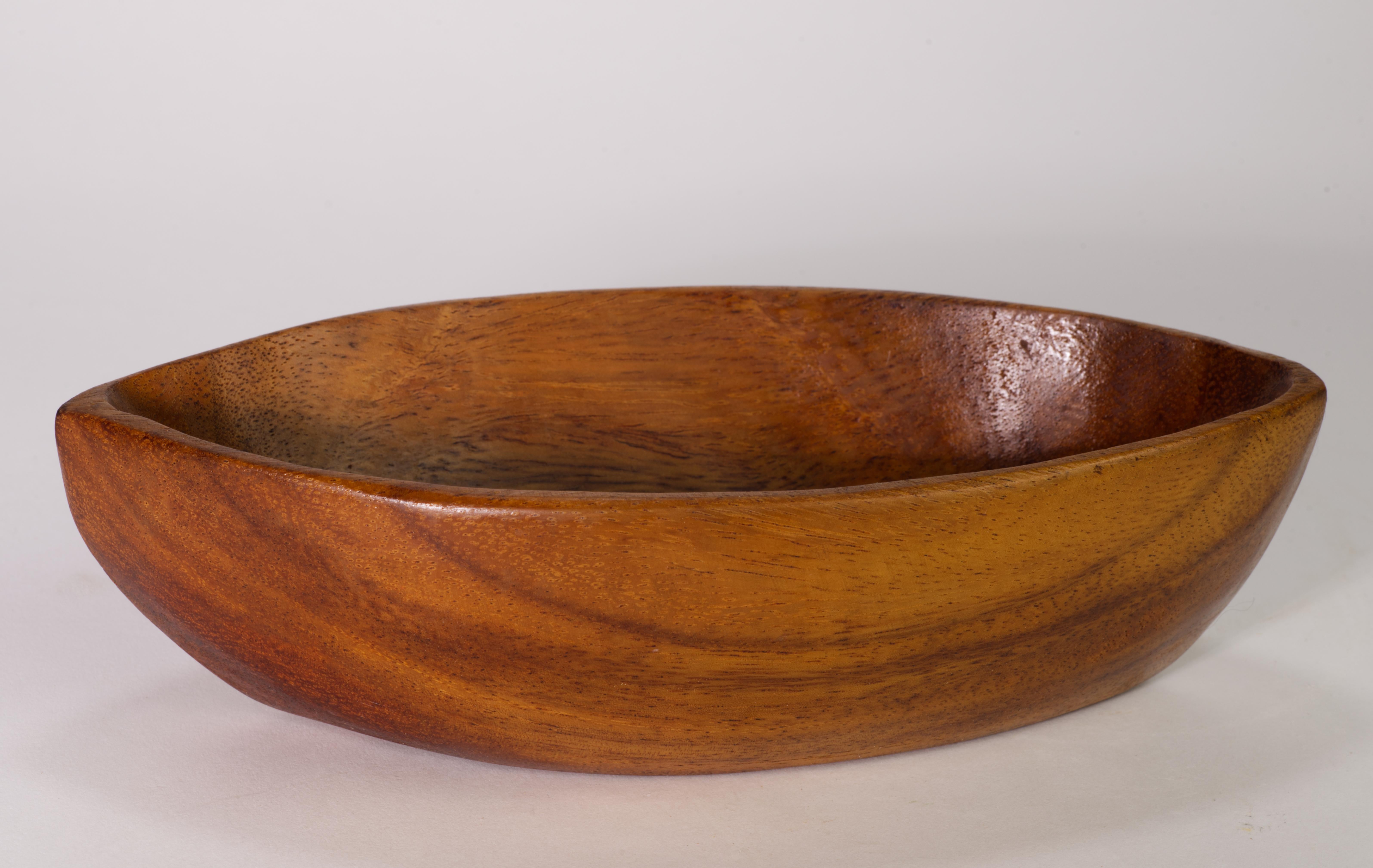  Vintage asymmetrical carved wooden bowl was hand made in Haiti from Taverneau, also known as Caribbean Walnut or False Tamarind, a durable tropical hardwood with a golden hue. It is done in style of Taverneau wood tray platters designed by Arthur