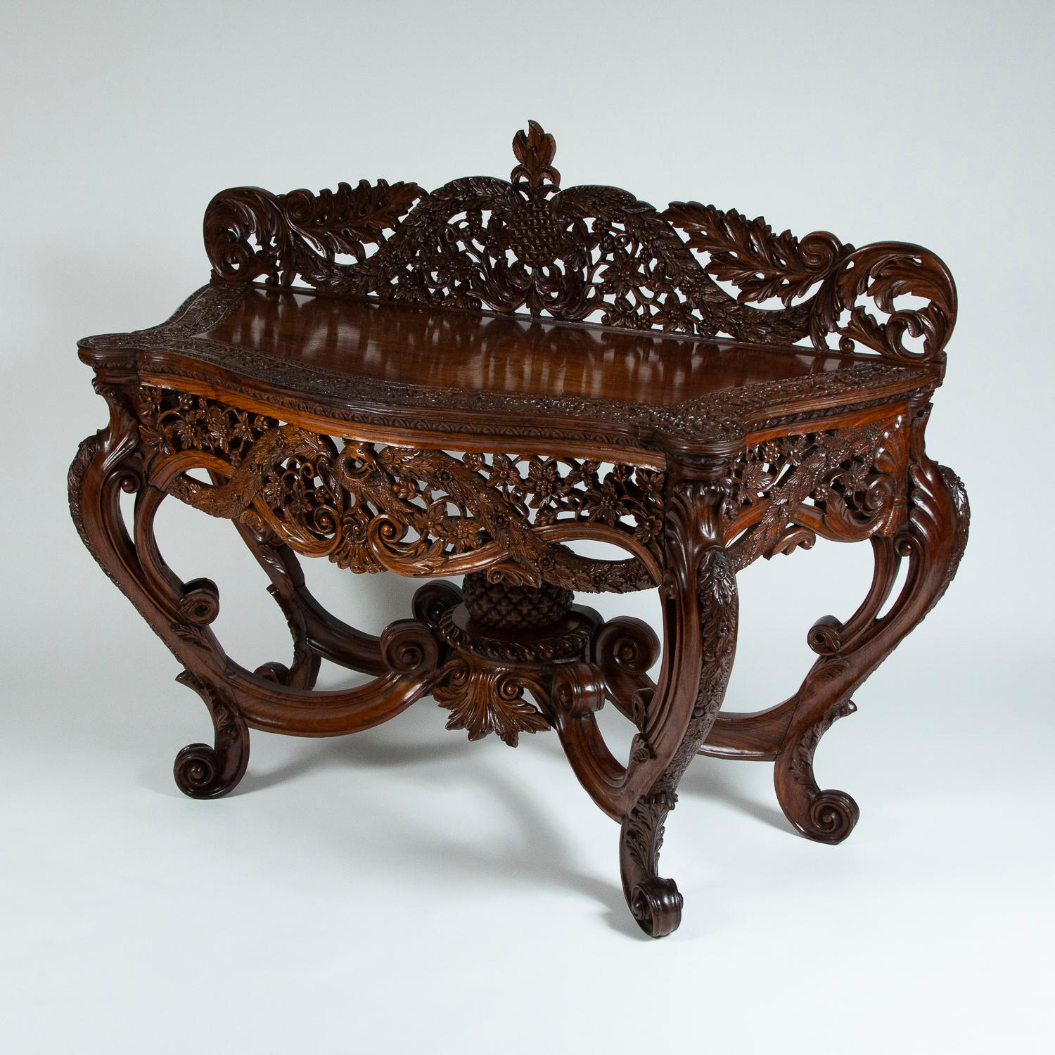 A late 19th century highly carved teak console table. 

Very ornate carving of pineapples, vines, phoenix, and jungle village scenes.