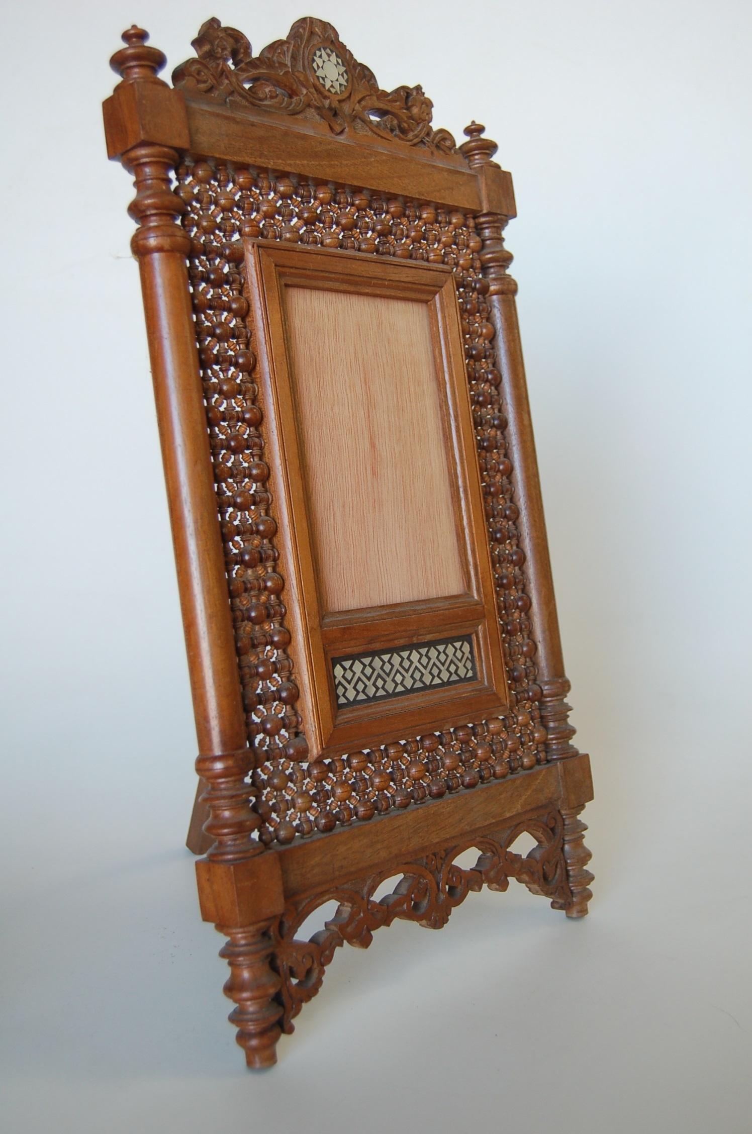 Intricate carved teak easeled table top mirror with mother of pearl.

A new high quality mirror will be added after purchase.

Measures: 18.5 high x 10