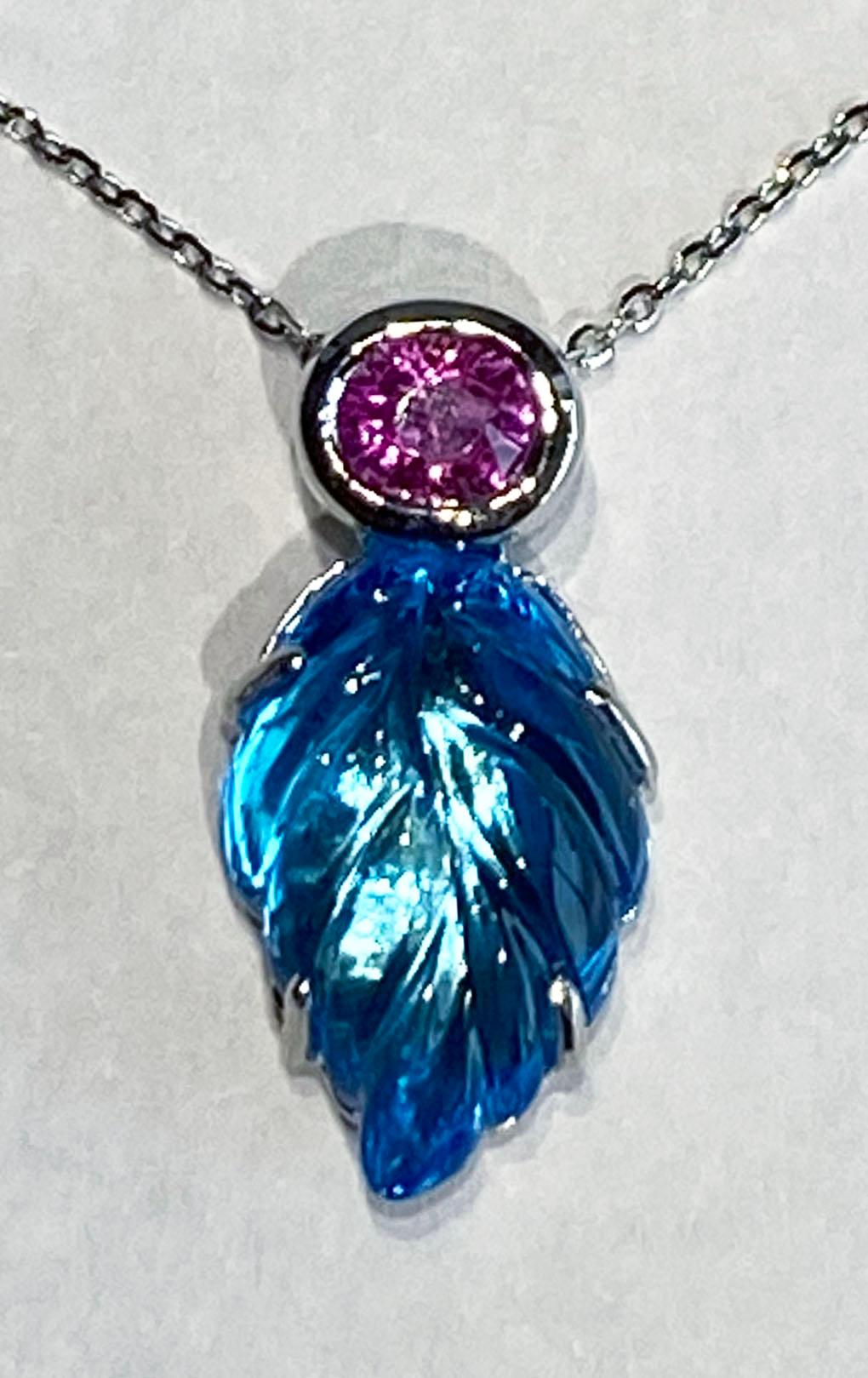 A Carved Topaz Pendant accented with Pink Sapphire set in 14kt White Gold. This 4.95 carat Topaz is carved as a leaf. The chain is an 18kt white gold chain that can adjust to 16